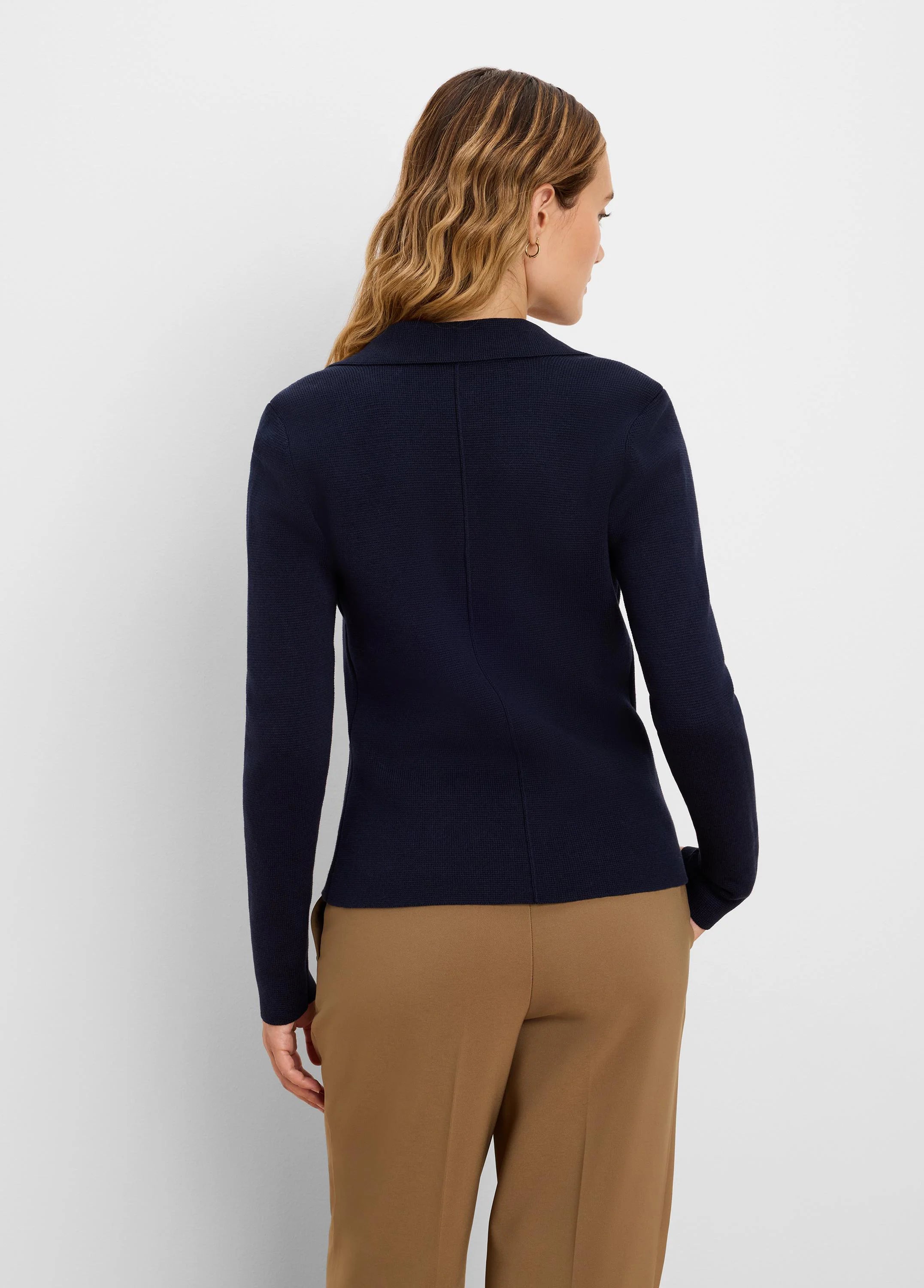 Navy knit tailored blazer, seen from behind. Features a notched collar, subtle ribbed texture, and a vertical back seam.
