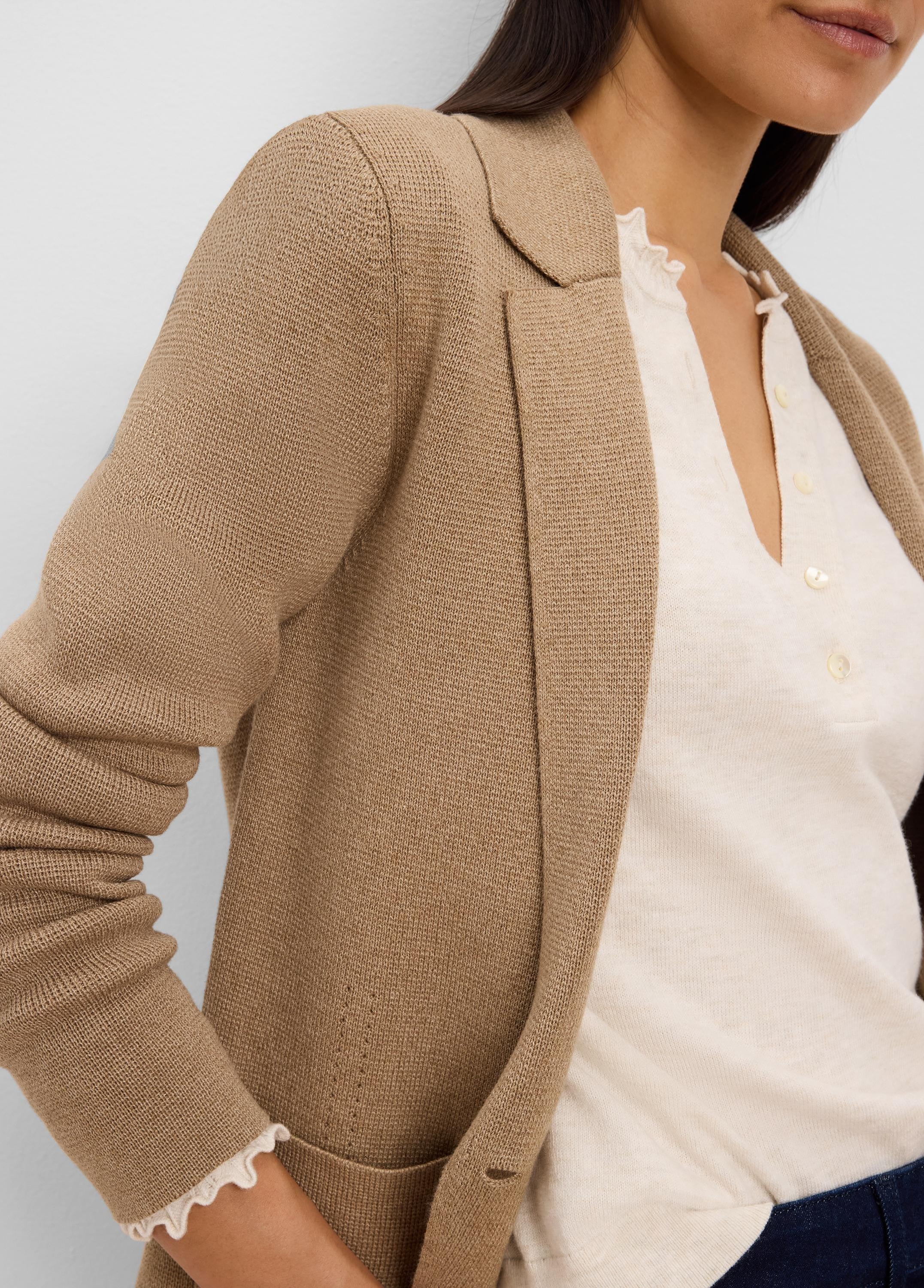 Camel knit tailored blazer with lapels and visible knit texture, worn over a cream shirt.