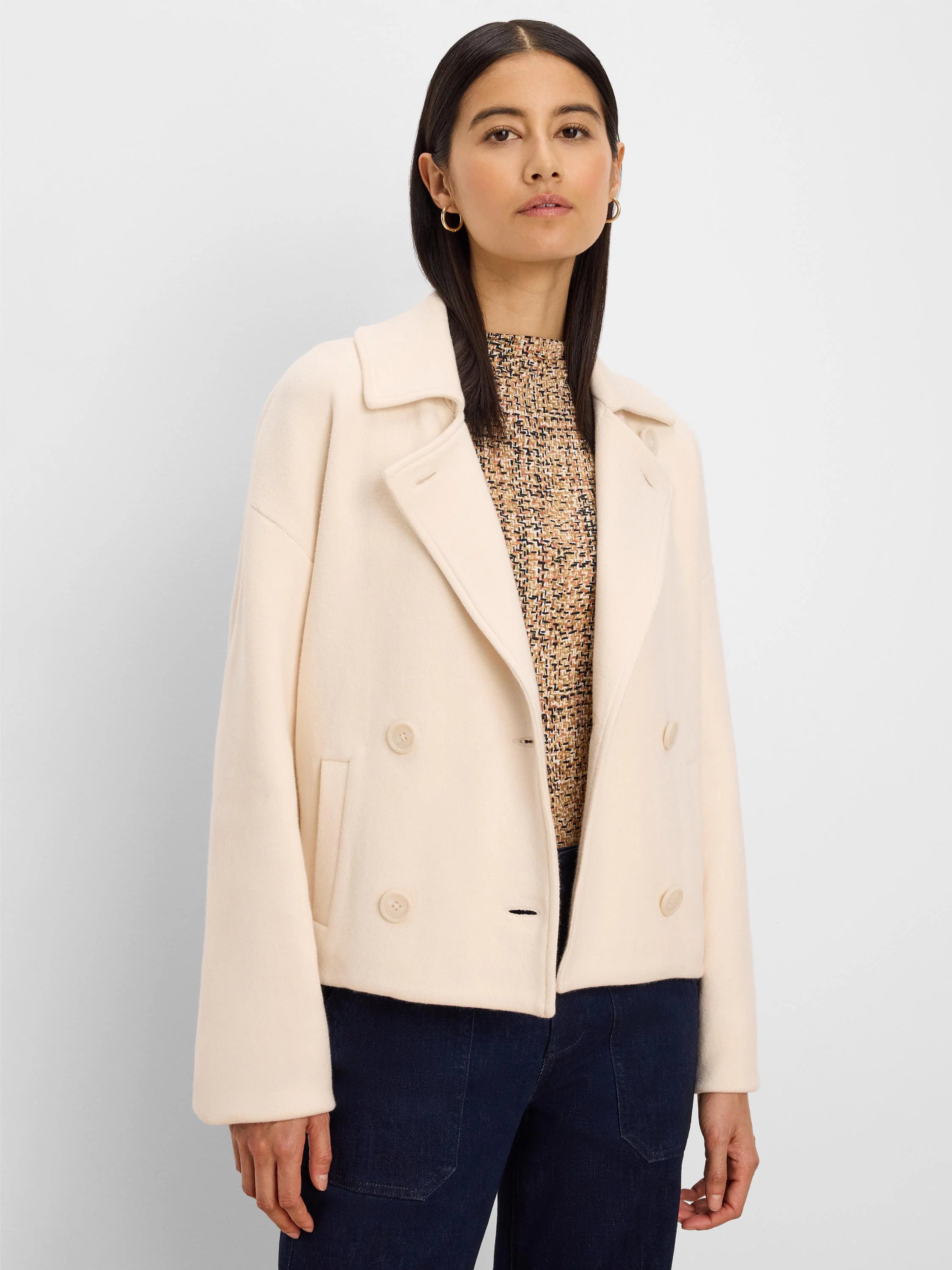 Cream double-breasted knit jacket with notched lapels, a welt pocket, and a short, cropped length.