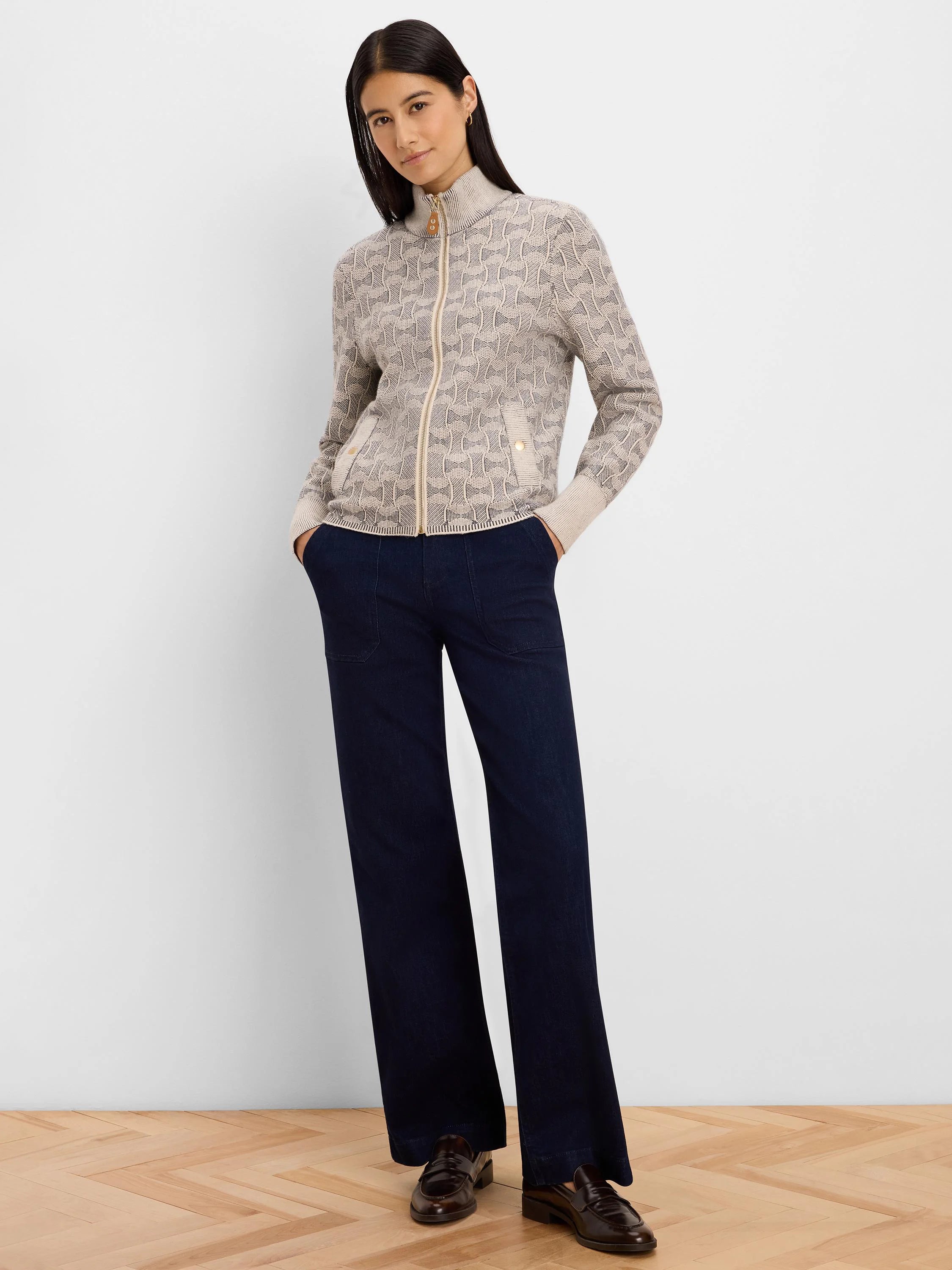 Beige knit jacket with dark swirl pattern, full gold zip, stand collar, and two buttoned pockets.
