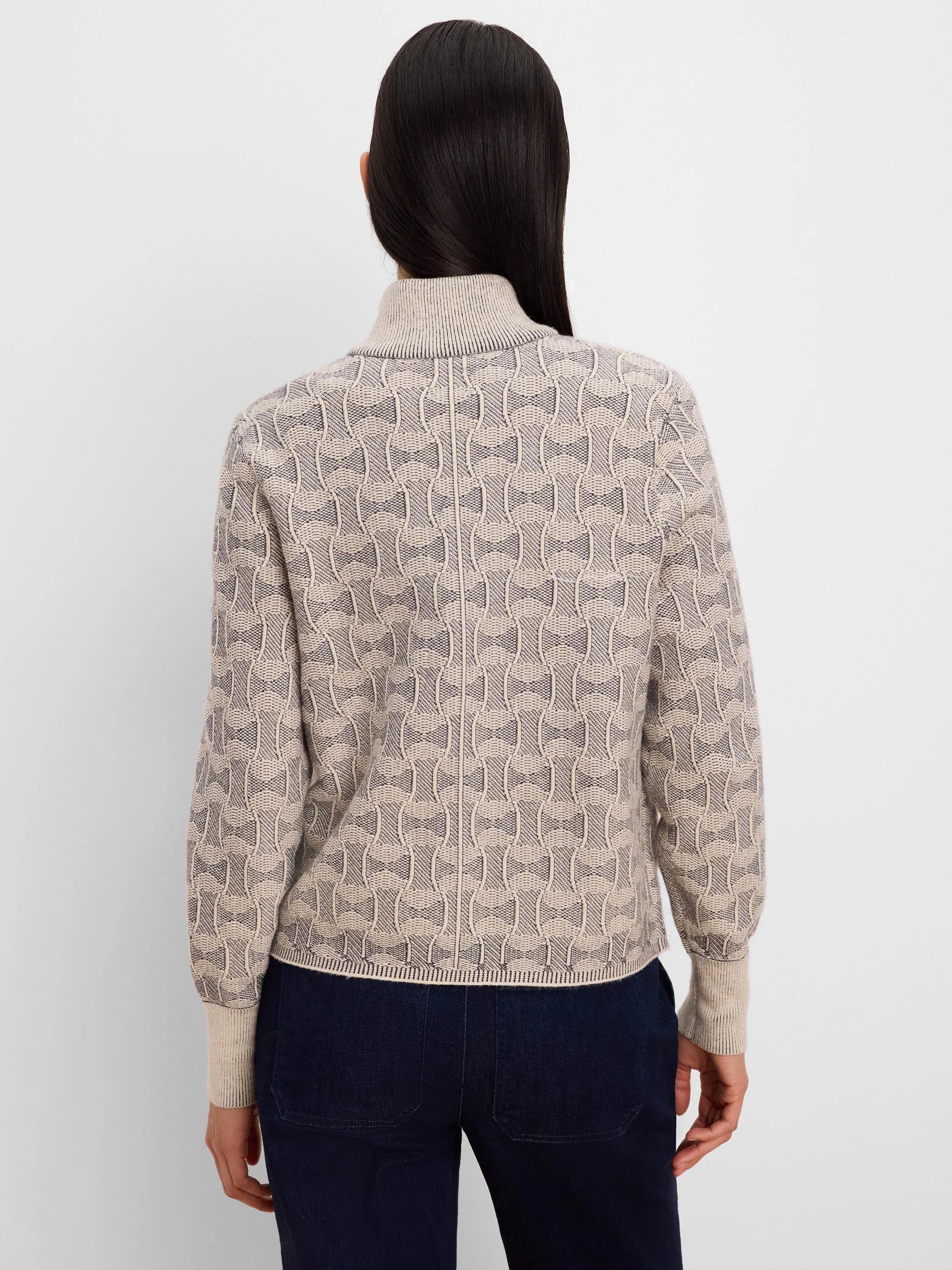 Beige knit jacket with dark grey interlocking ovals pattern. Ribbed turtleneck, cuffs, and hem.