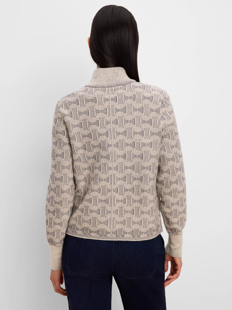 Beige knit jacket with dark grey interlocking ovals pattern. Ribbed turtleneck, cuffs, and hem.
