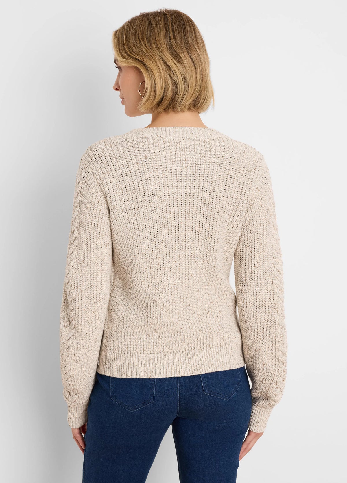 Cream flecked shaker knit cardigan with cable pattern on sleeves, shown from the back.