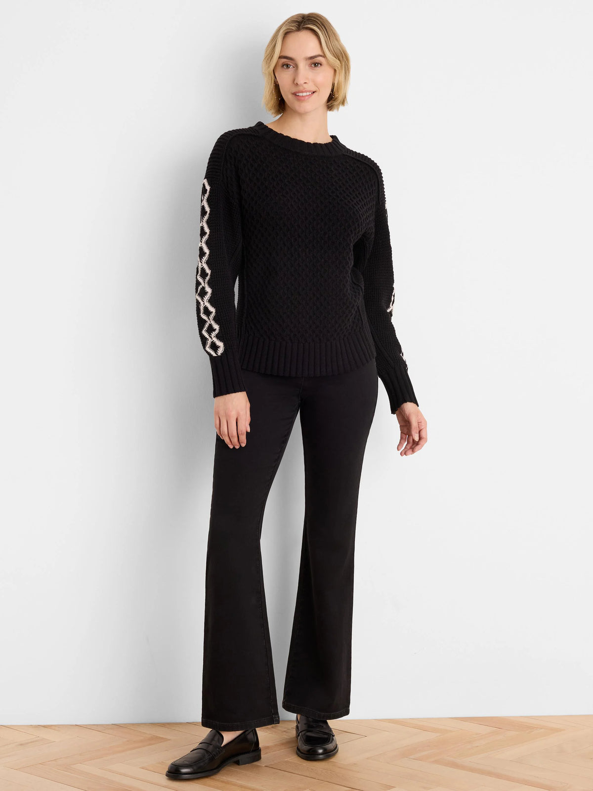 Black knit sweater with raised texture. Off-white criss-cross pattern on sleeves; ribbed cuffs & hem.