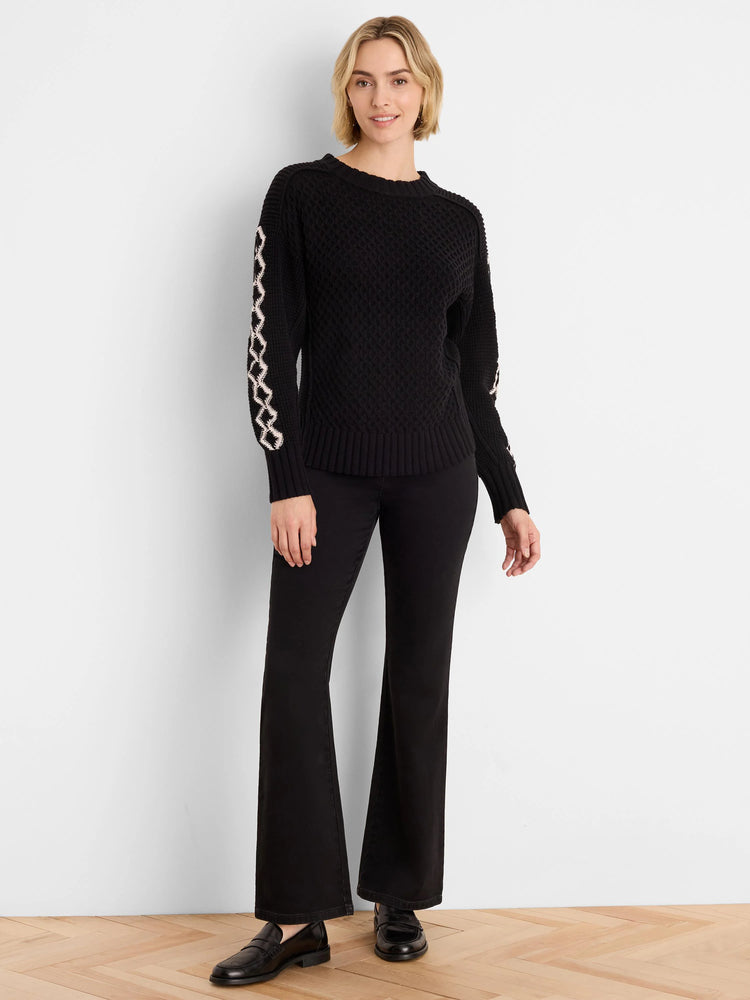 Black knit sweater with raised texture. Off-white criss-cross pattern on sleeves; ribbed cuffs & hem.
