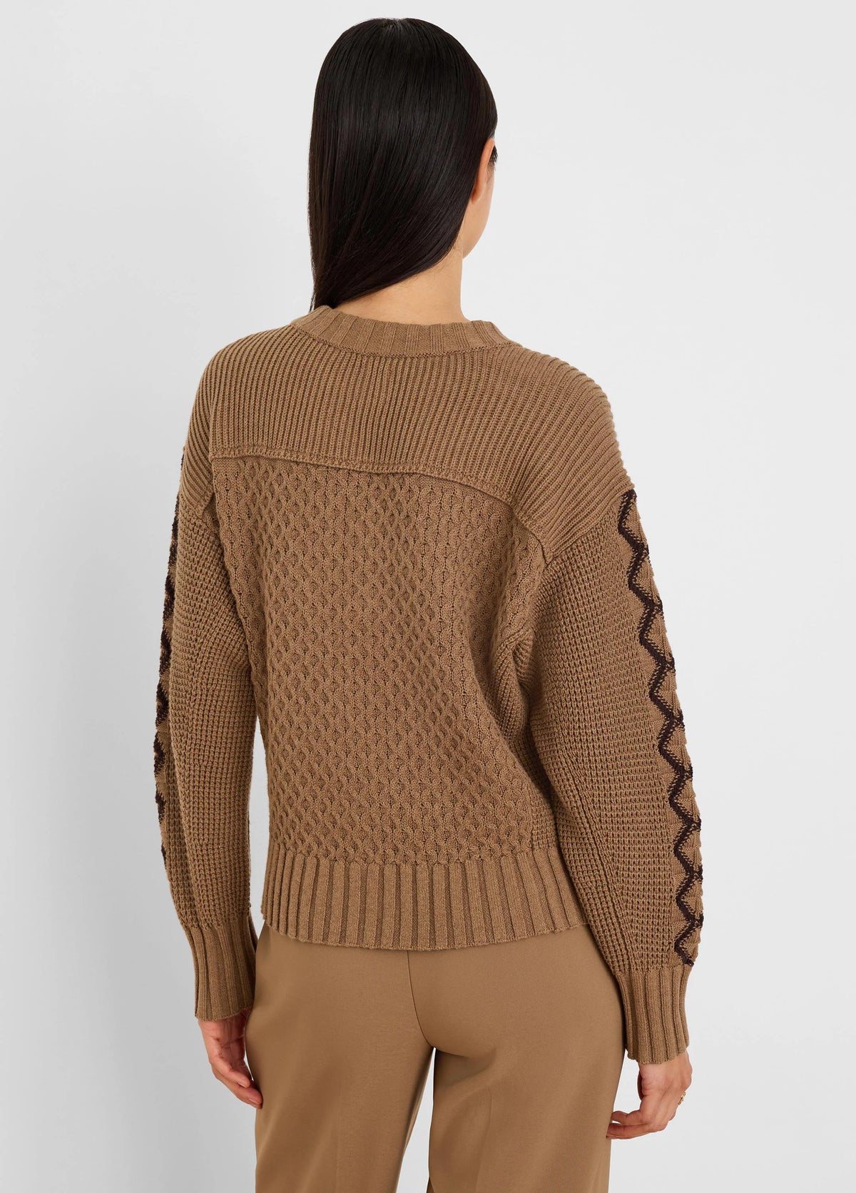 Camel brown sweater features ribbed edges, a textured diamond knit body, and dark zig-zag patterns on the sleeves.