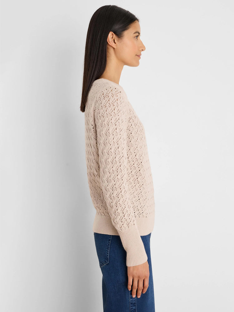 Light beige sweater with an open patterned knit texture, ribbed cuffs and hem.