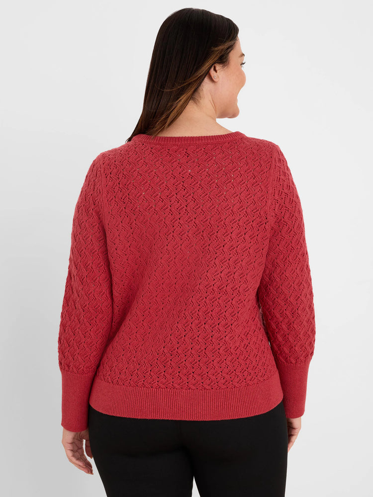 Deep red knit sweater with an all-over open diamond stitch pattern. Has long sleeves, ribbed cuffs, and hem.