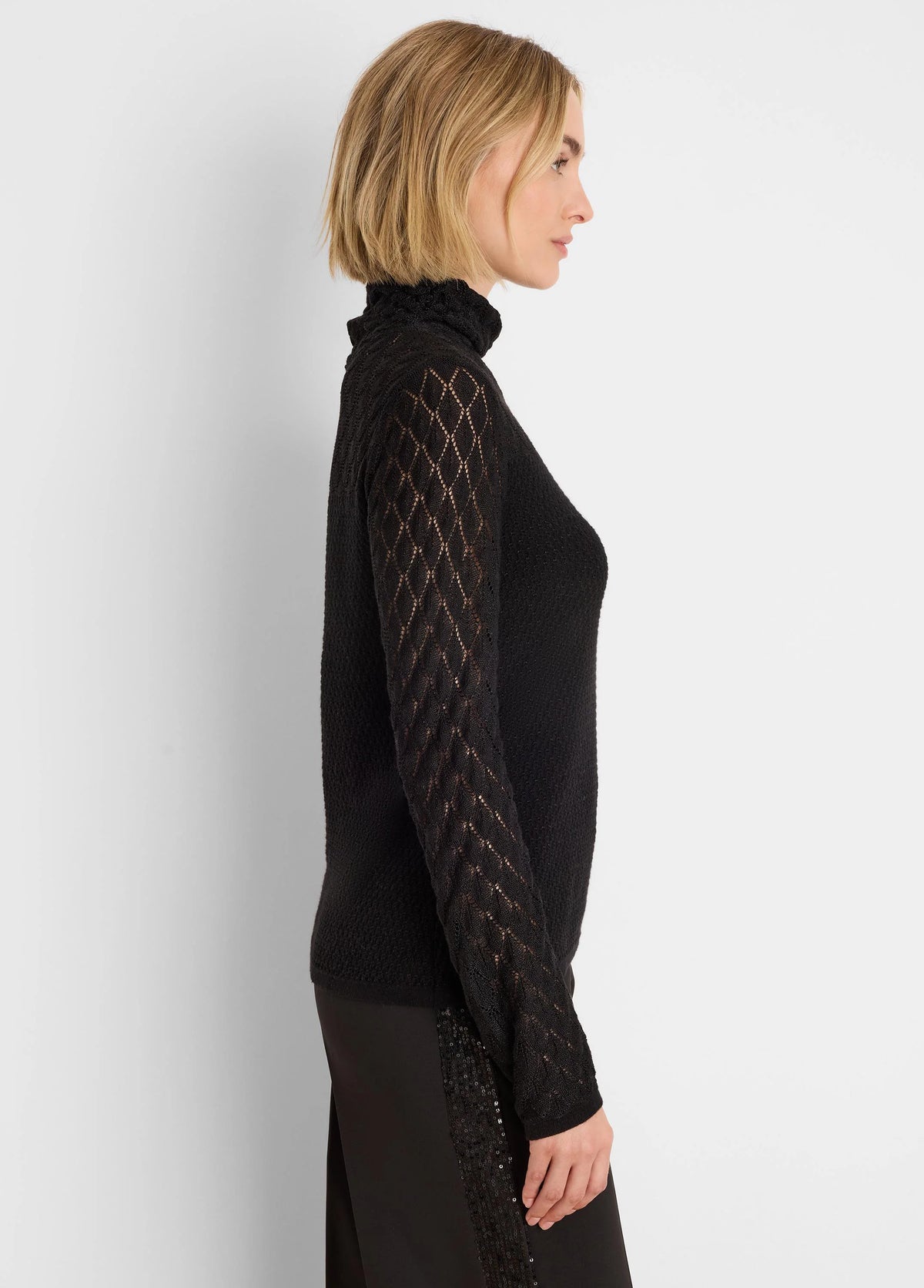 Black knit turtleneck sweater with open diamond lace knit sleeves.