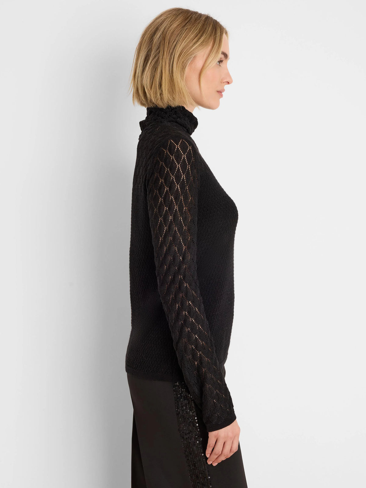 Black knit turtleneck sweater with open diamond lace knit sleeves.