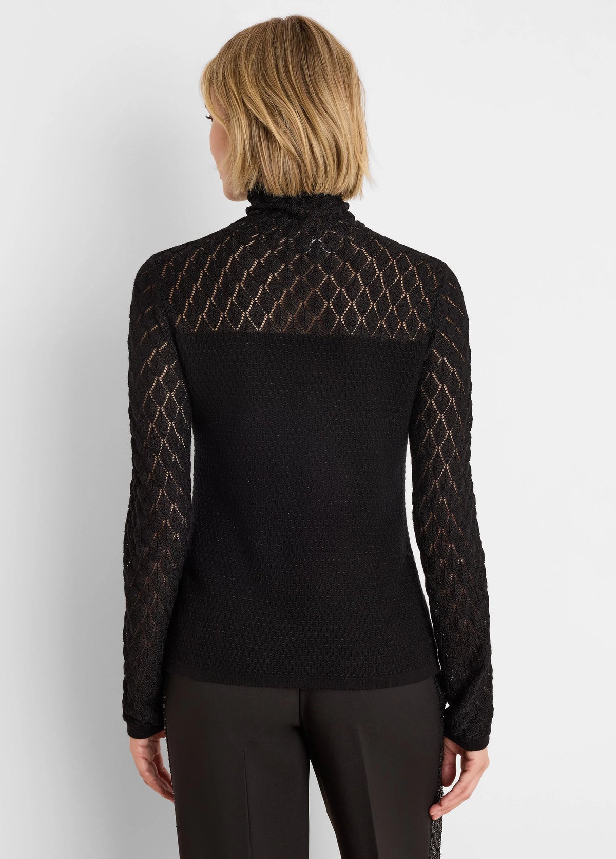 Black knit lace turtleneck sweater. Sheer diamond lace pattern on sleeves and upper back; opaque knit torso.