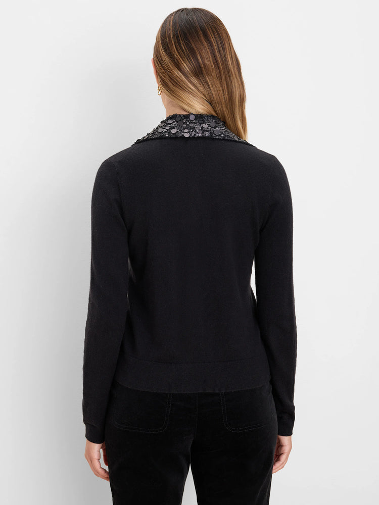 Black cardigan with dark sequin collar, long sleeves, and ribbed trim, worn by a model from the back.