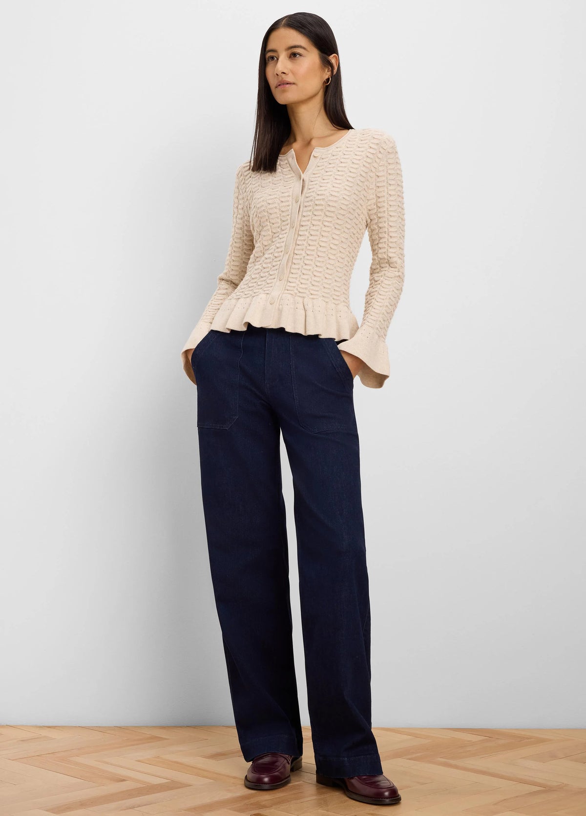 Cream button-front cardigan with a wavy textured knit pattern and a gathered, frilled hem.