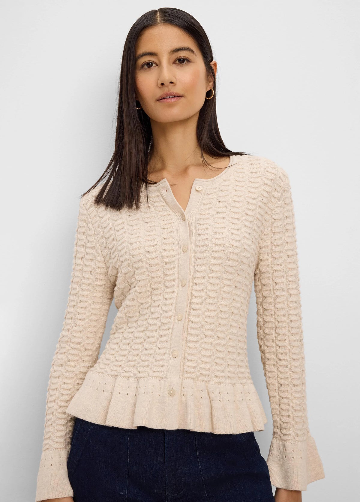 Cream textured knit cardigan with button front, V-neck, ruffled peplum hem, and flared cuffs.