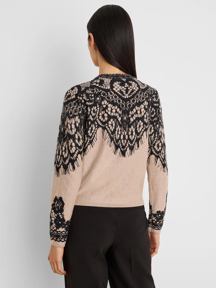 Beige cardigan with intricate black lace-like print across the upper back and sleeves. Model shown from behind.