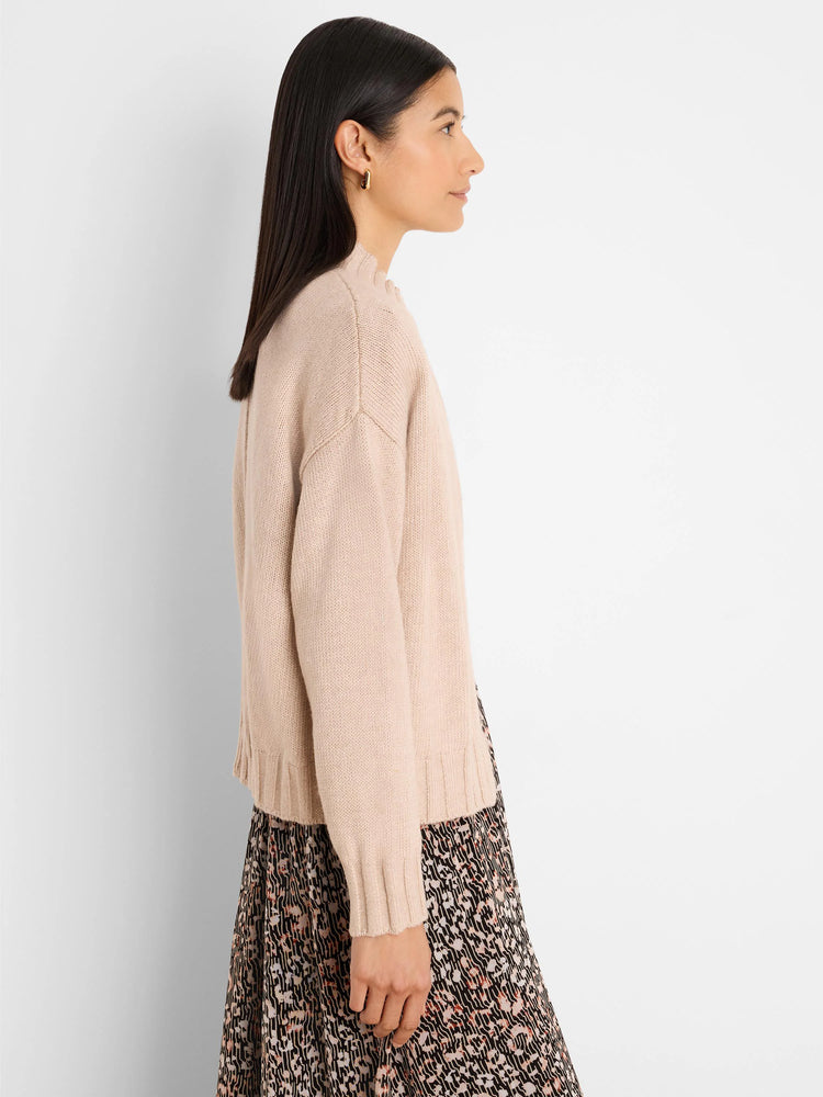 Light beige knitted cardigan with ribbed cuffs, hem, and a ruffled mock neck.