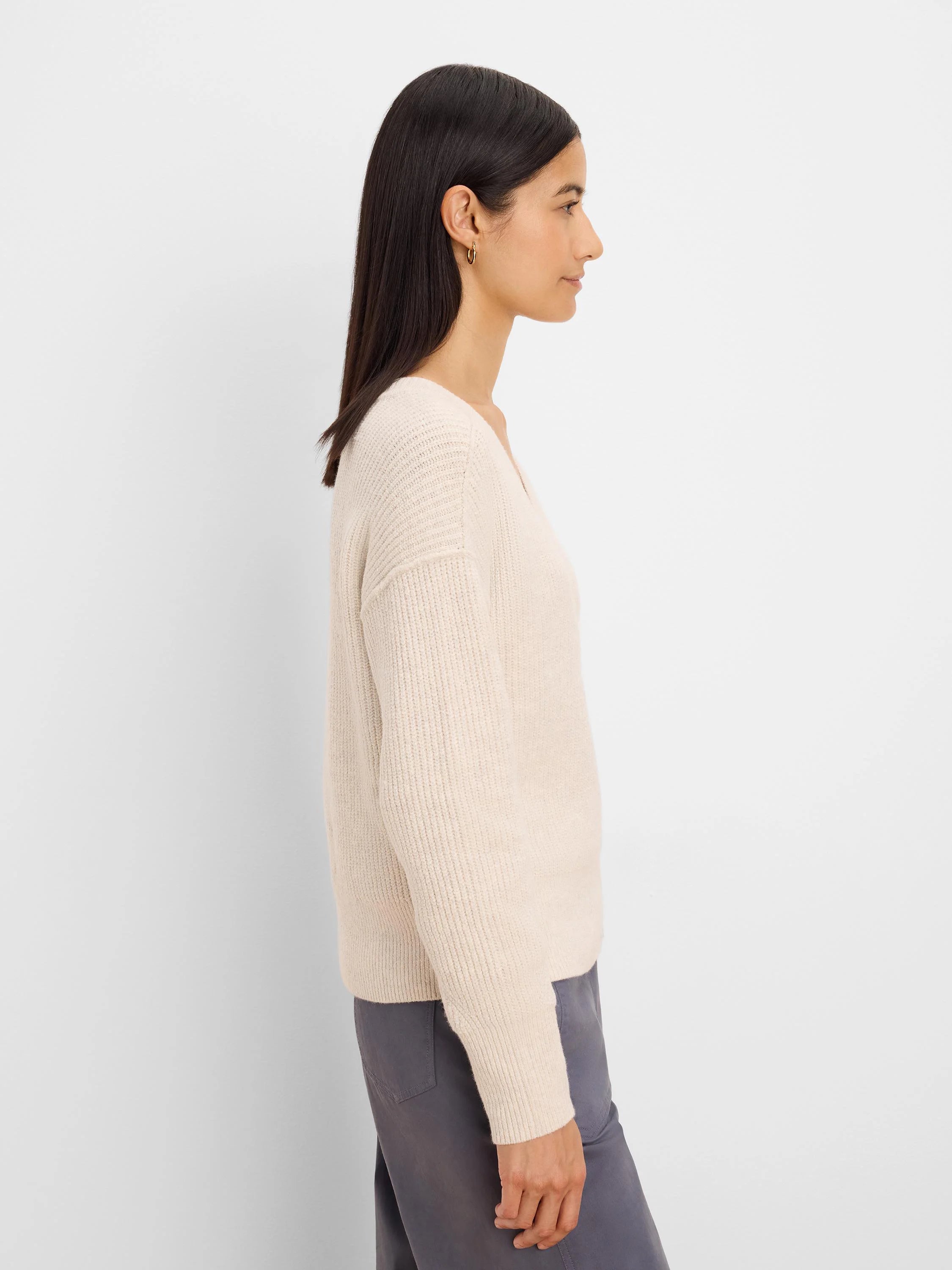 Light beige, soft knit V-neck sweater with ribbed sleeves.