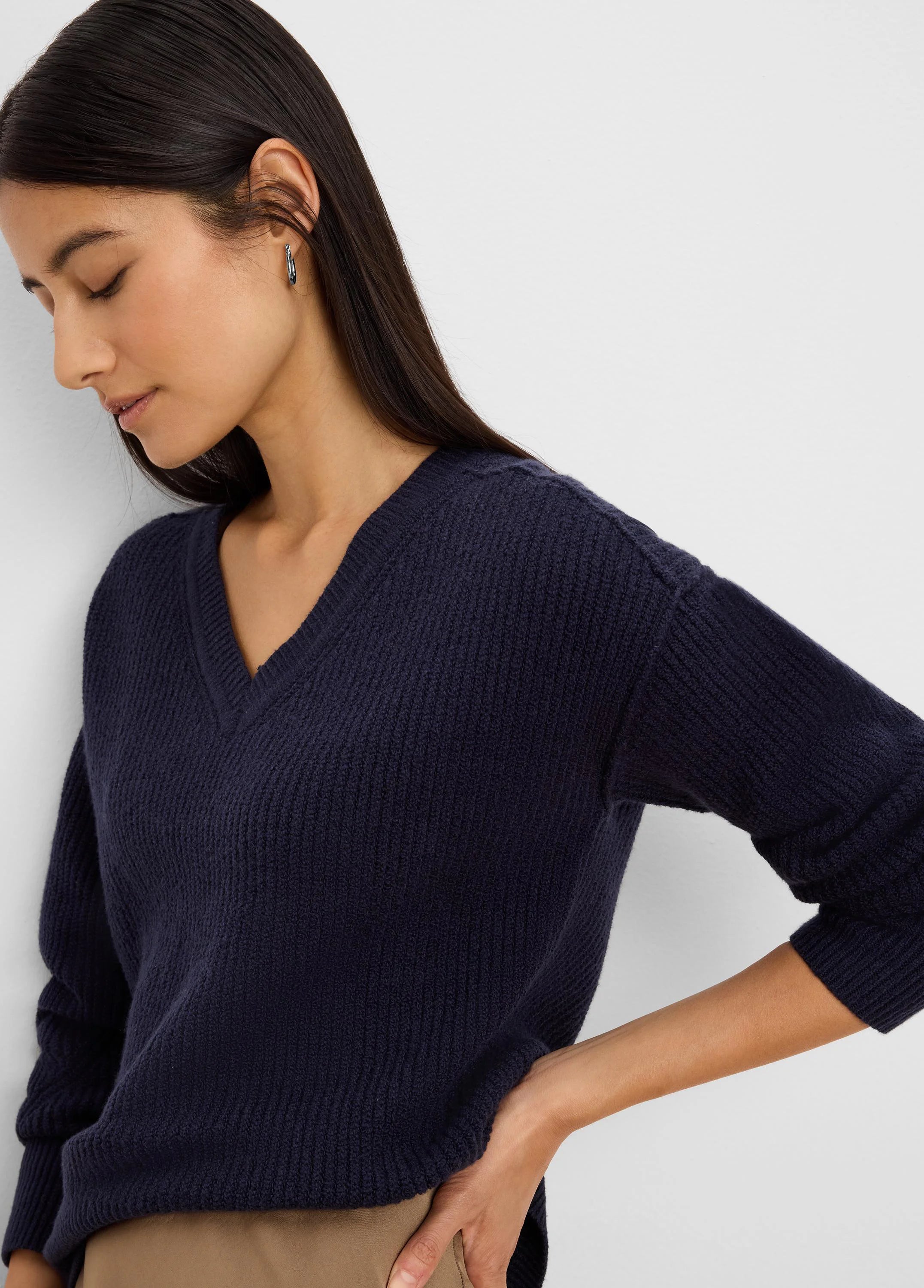 Navy V-neck sweater with a textured, ribbed knit. Features a relaxed fit on the model.