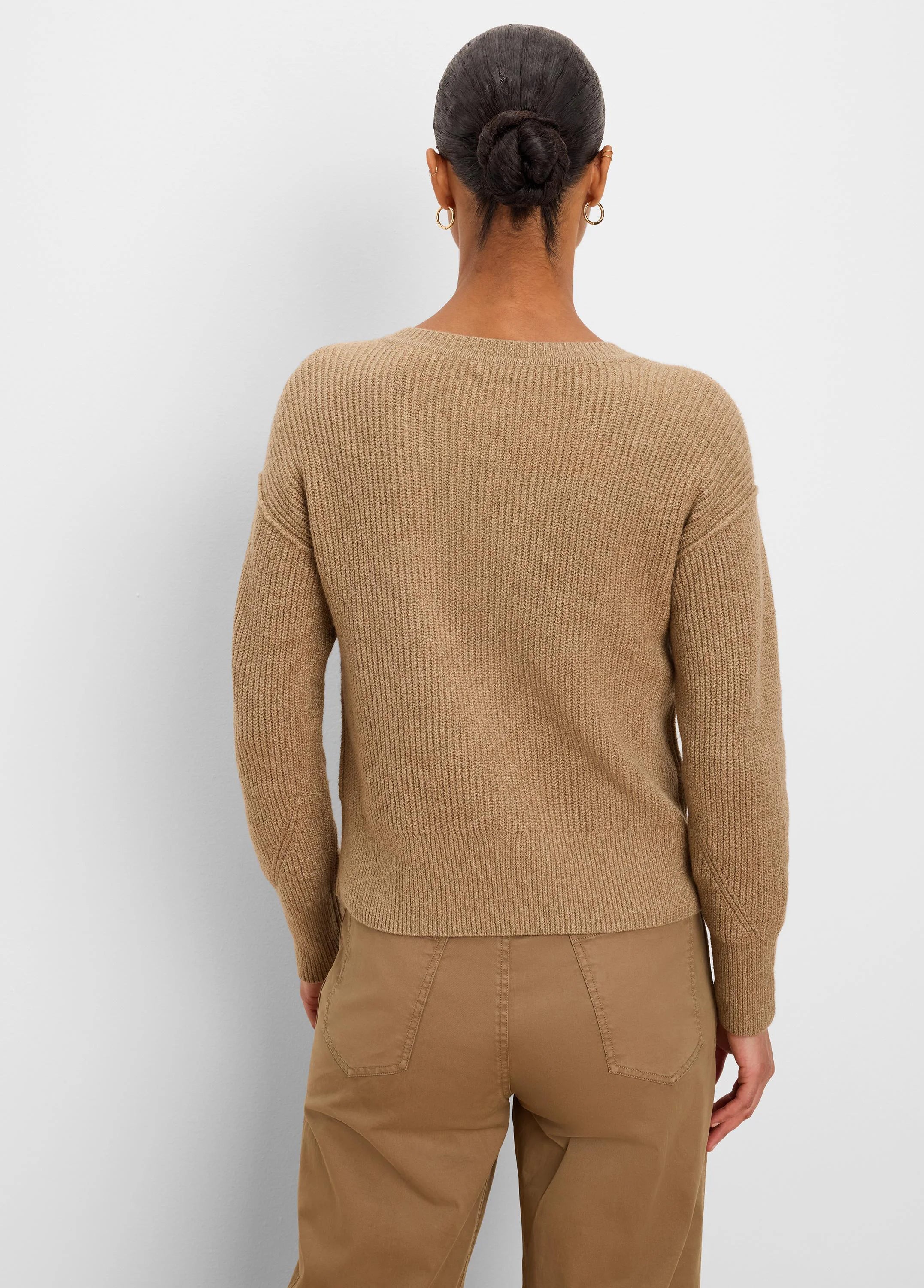 Back of model wearing a tan ribbed knit sweater. Features a crewneck, long sleeves, and a ribbed hem.