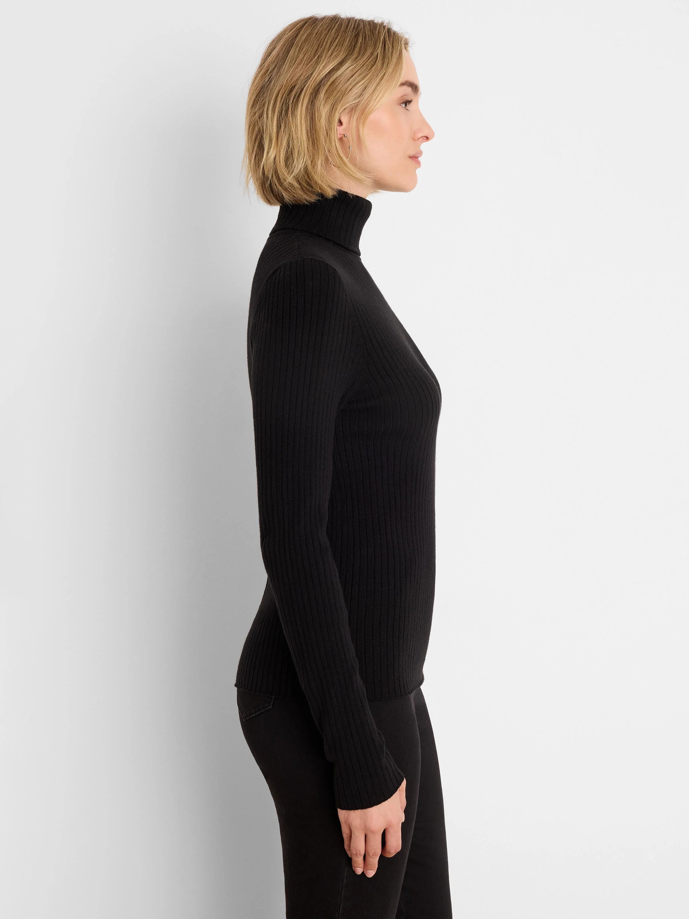 Black ribbed knit turtleneck sweater, slim fit, shown on a model in profile.