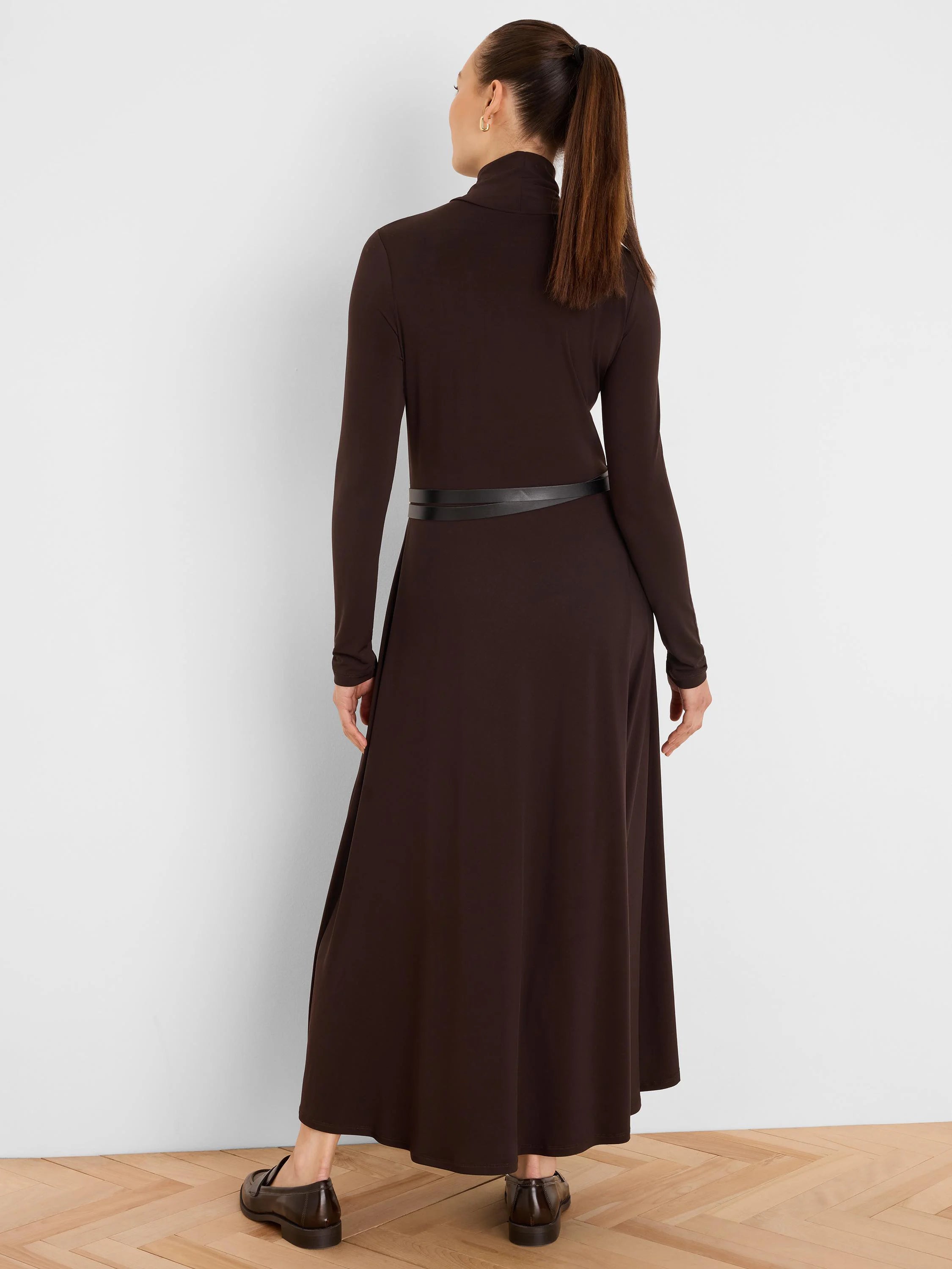 Dark brown high-neck maxi dress with long sleeves, shown from back. Features a thin black double-wrap belt.