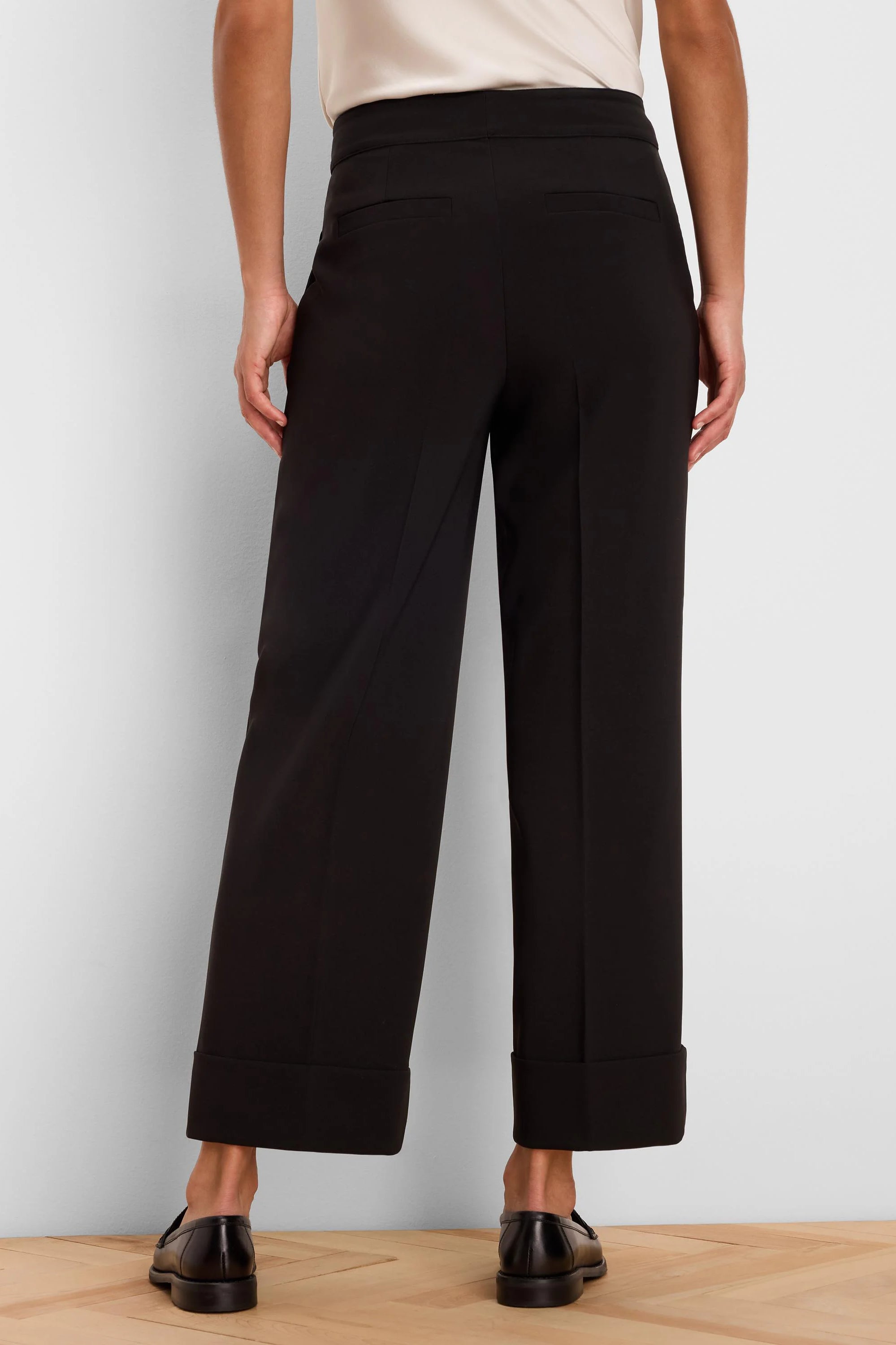 Black wide-leg ankle pants with cuffed hems and two back welt pockets, shown from the rear.
