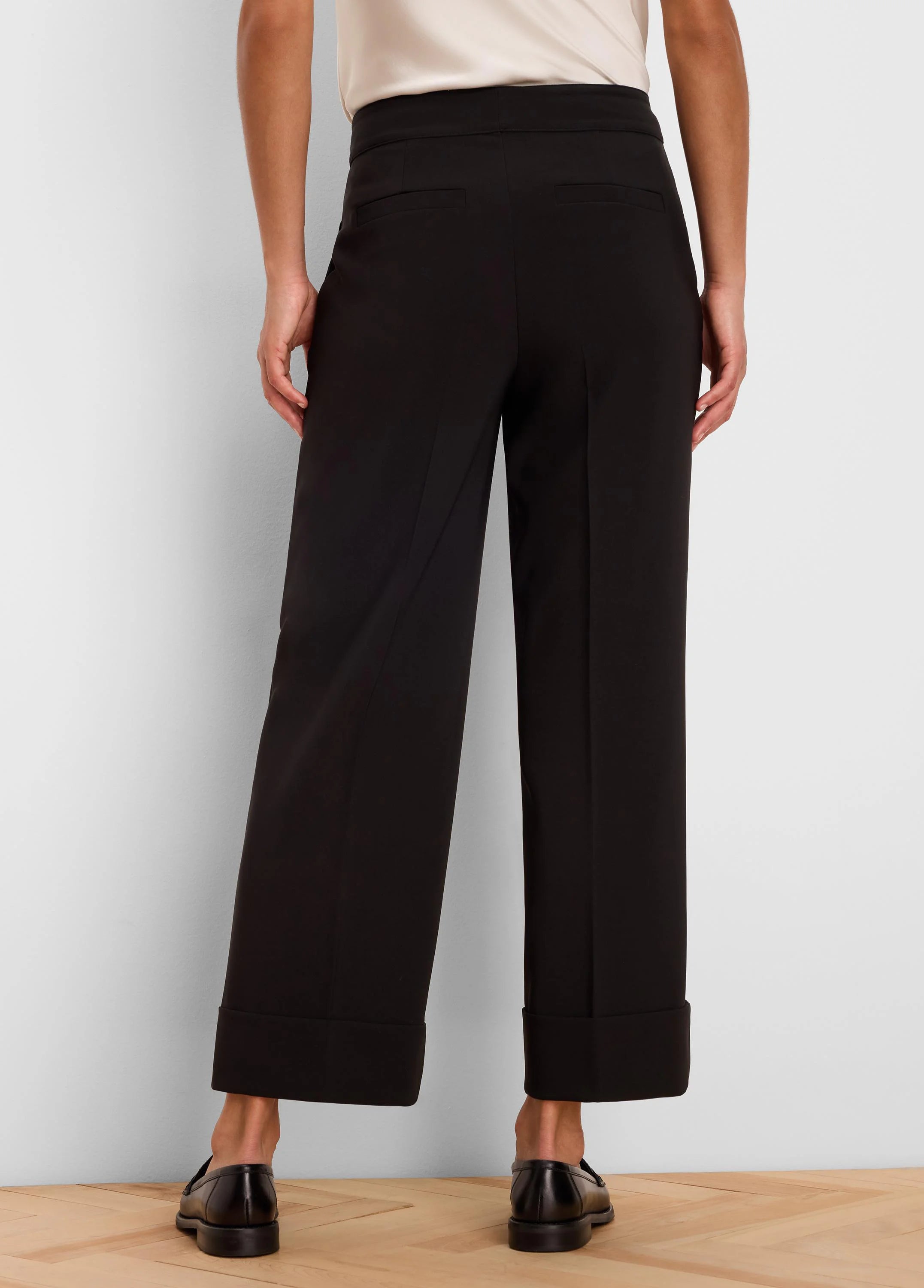 Black wide-leg ankle pants with cuffed hems and two back welt pockets, shown from the rear.