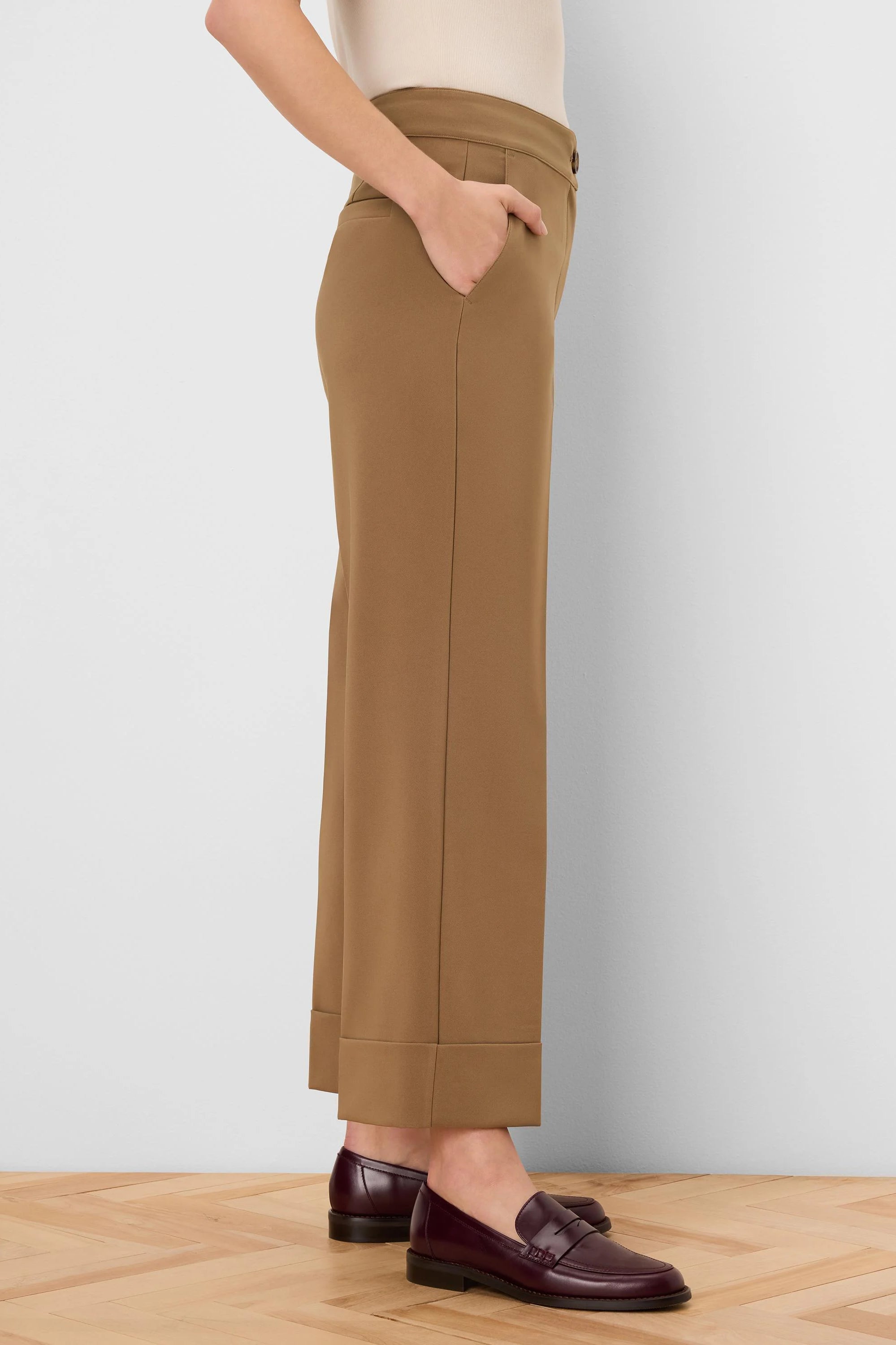 Tan sleek stretch pants with cuffed ankles and visible side pockets.