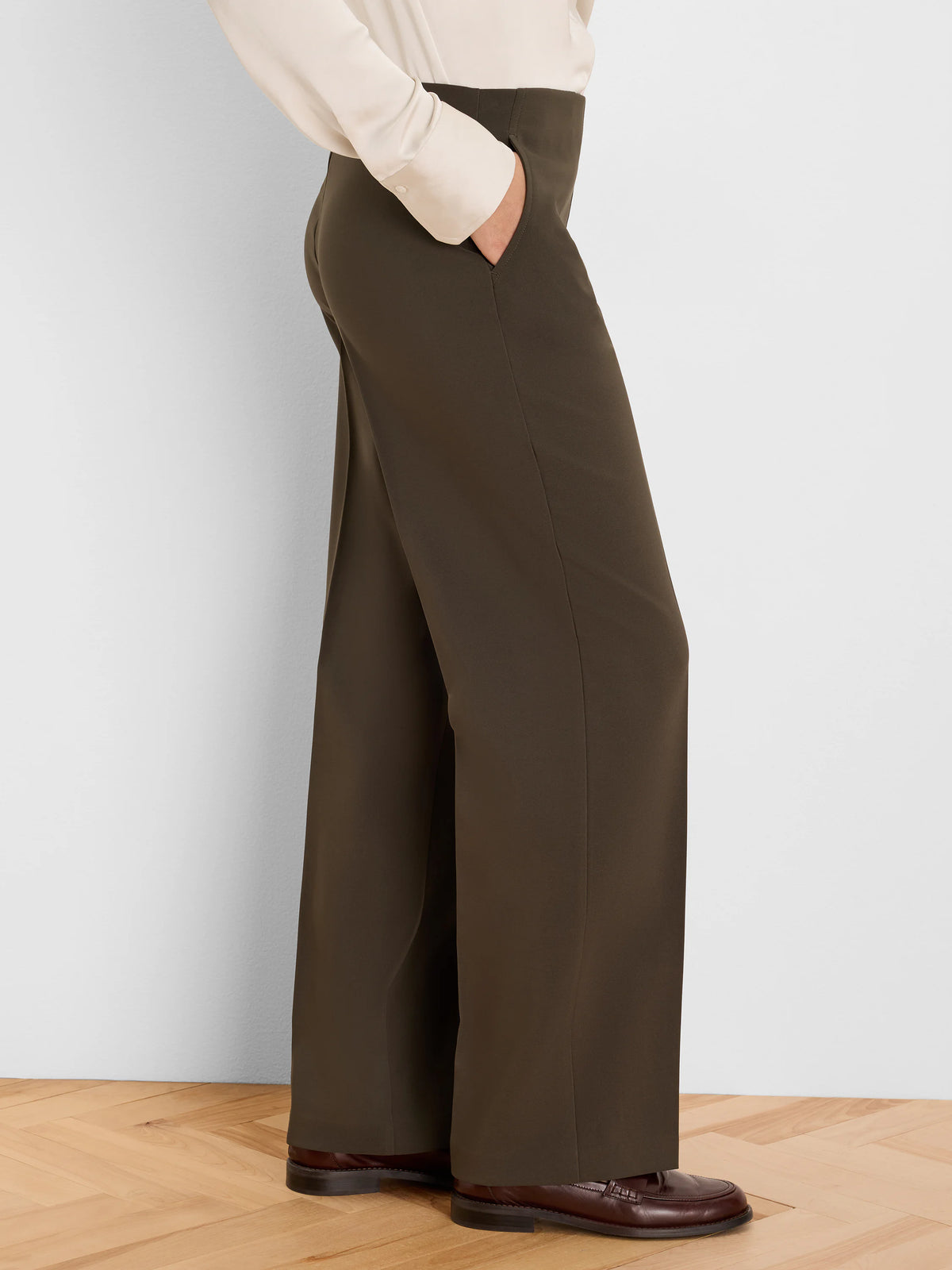 Deep olive green wide-leg pants, high-waisted with a smooth drape. A hand rests in the side pocket.