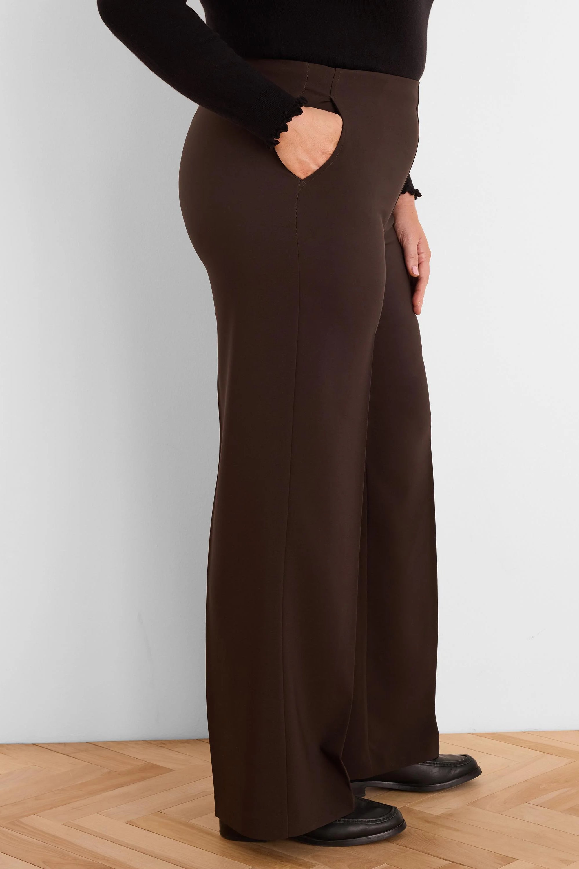 Dark brown, sleek wide-leg pants with side pockets, modeled from the side.