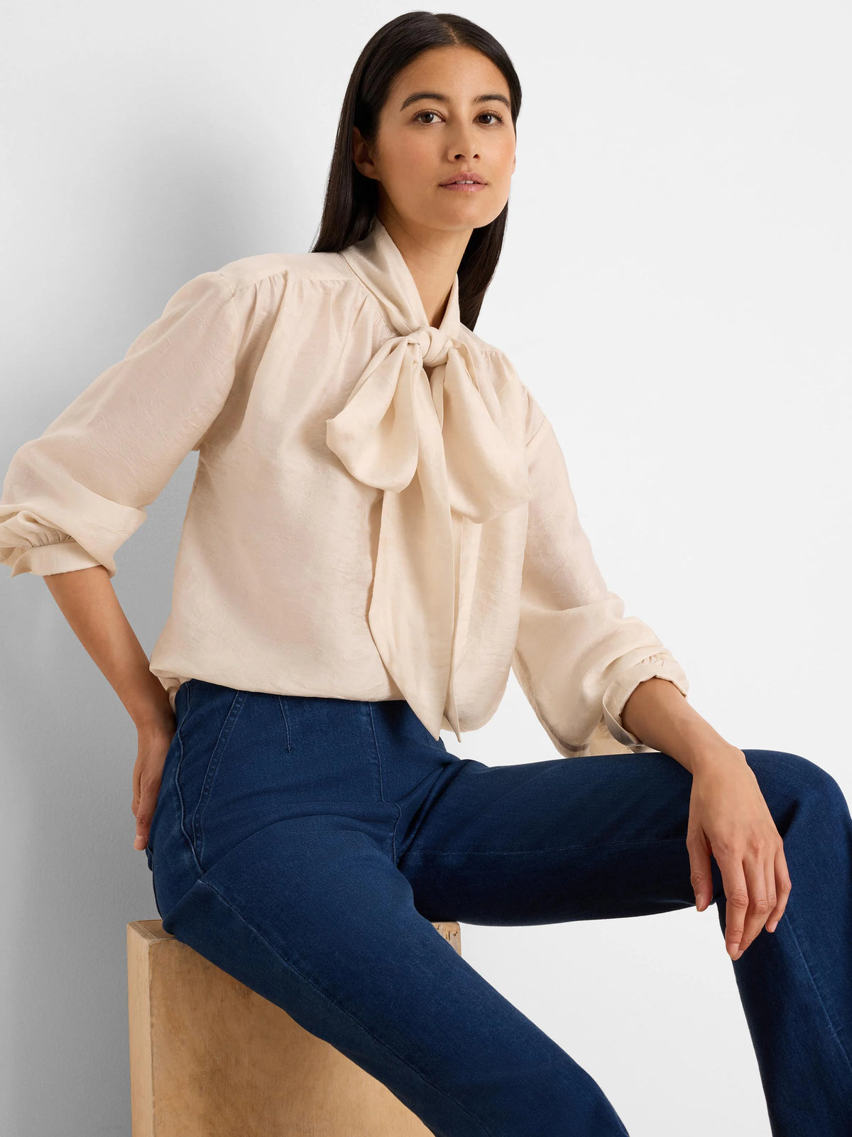 Pale cream crinkle tie-neck top with a large bow detail and gathered long sleeves.