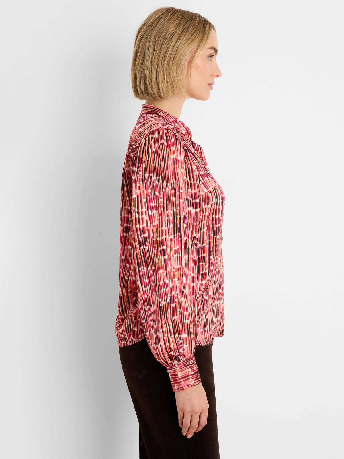 Red, orange, and dark-toned abstract vertical striped shirt with fine pleats and long cuffed sleeves.