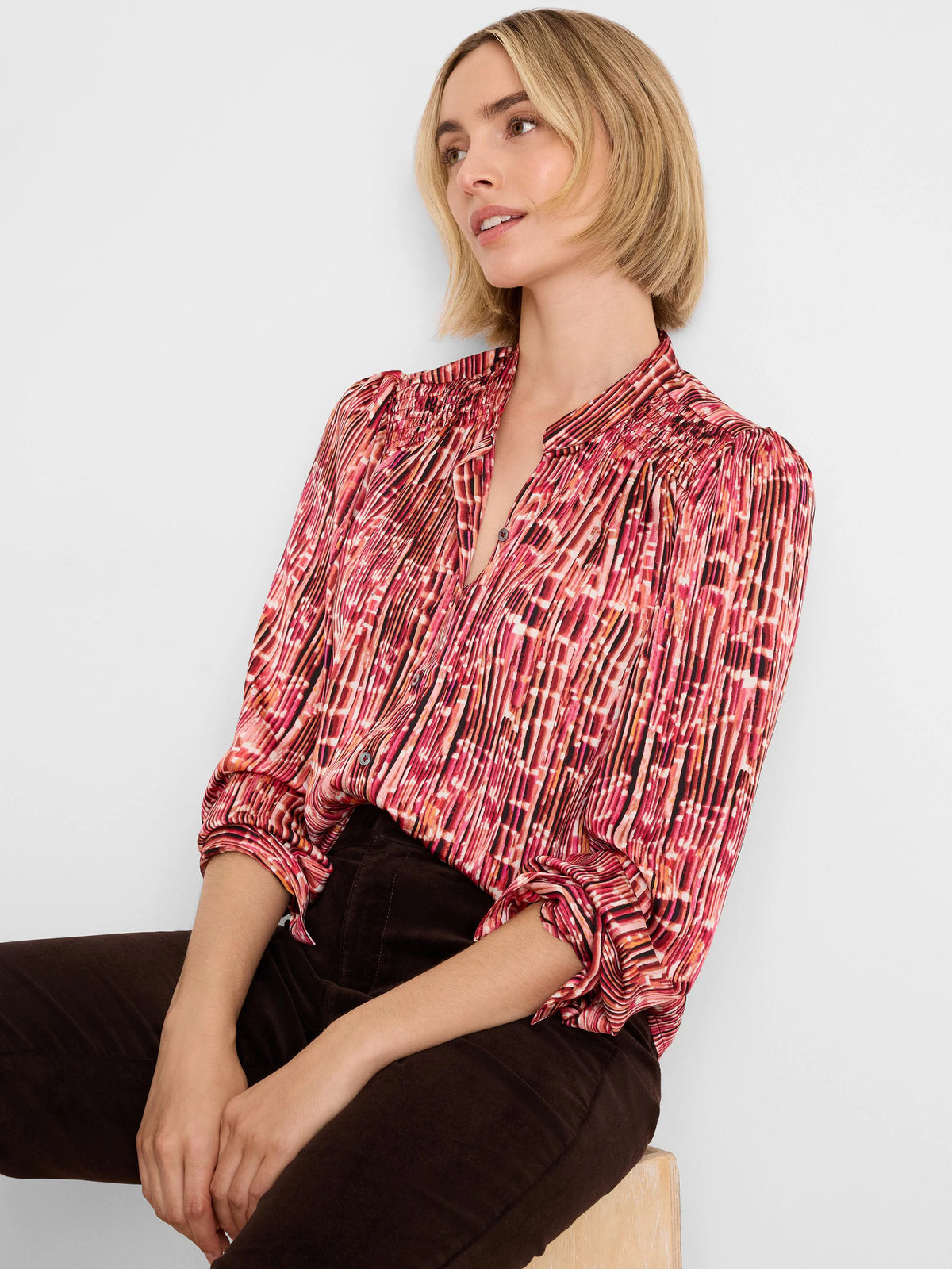 Red-orange geometric patterned shirt with smocked shoulders, mandarin collar, and vertical pleats.