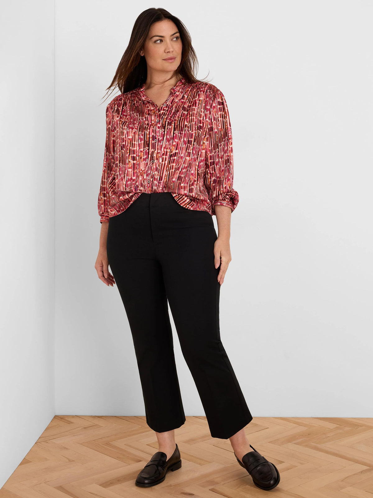 Red, pink, and orange abstract striped shirt with fine vertical pleats, collared and long sleeves rolled up.