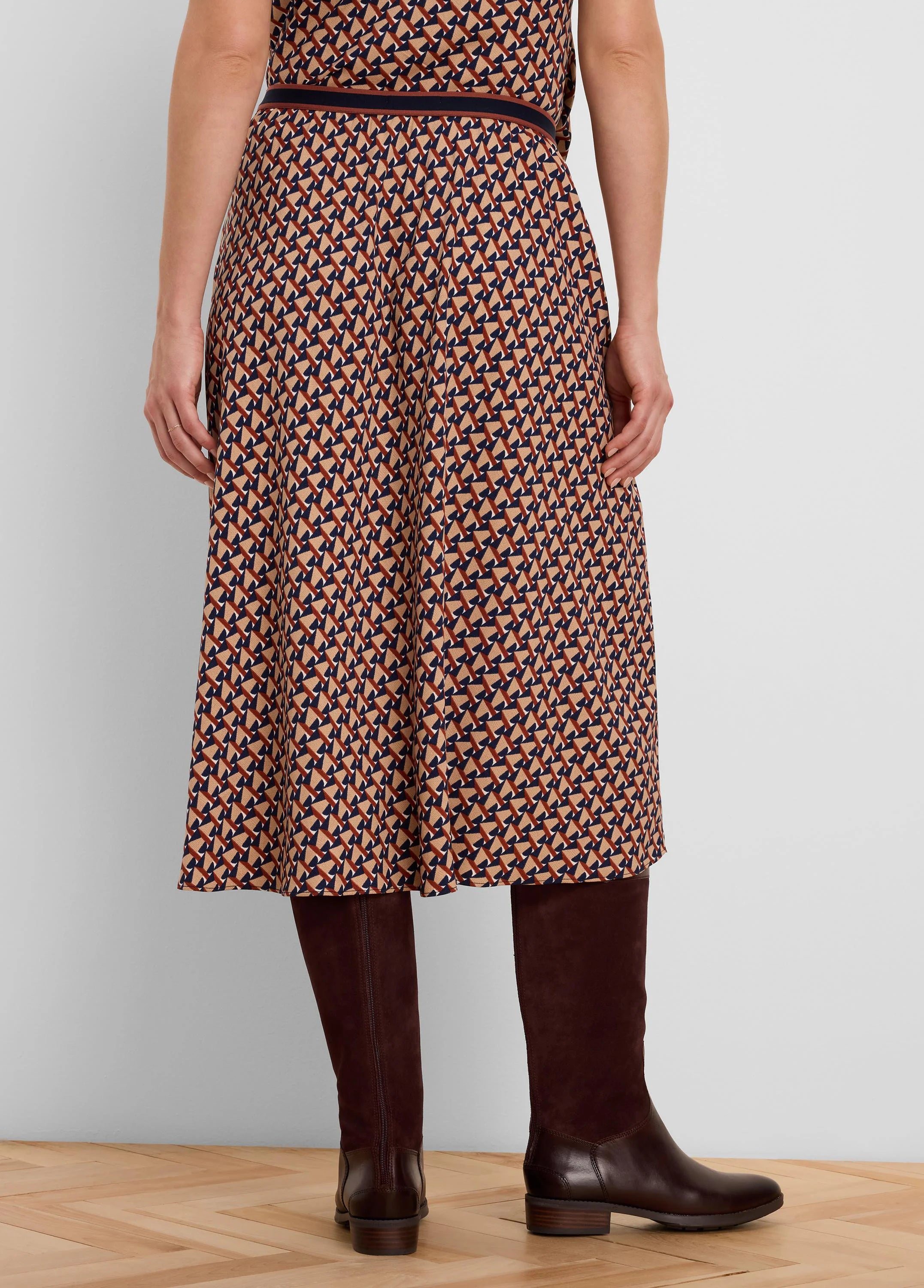 Midi skirt with a geometric tile pattern in beige, navy, and rust. Features a dark banded waist.