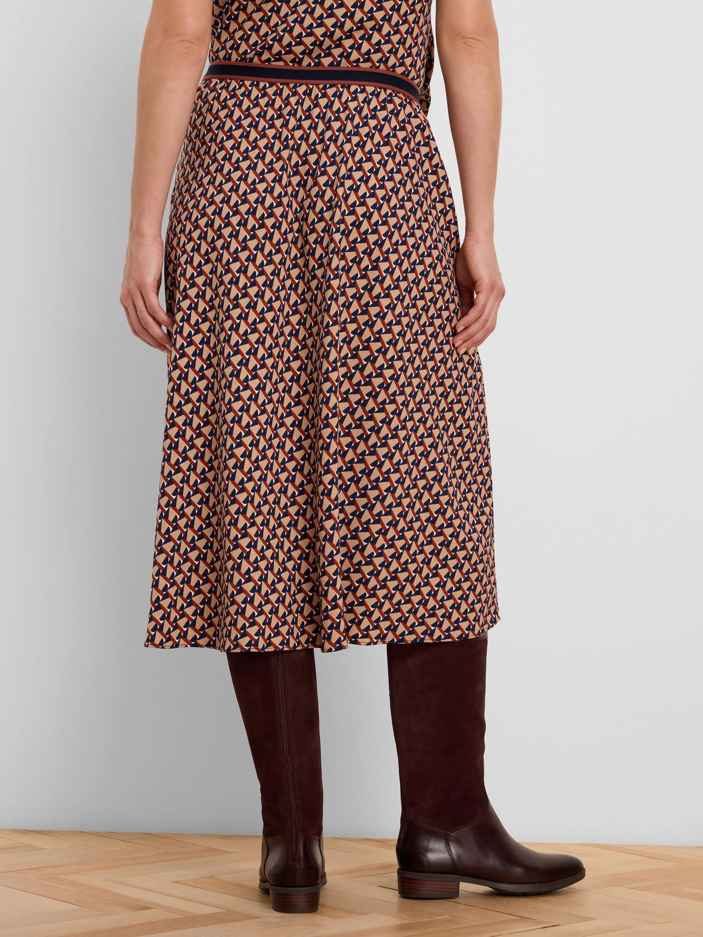 Midi skirt with a geometric tile pattern in beige, navy, and rust. Features a dark banded waist.