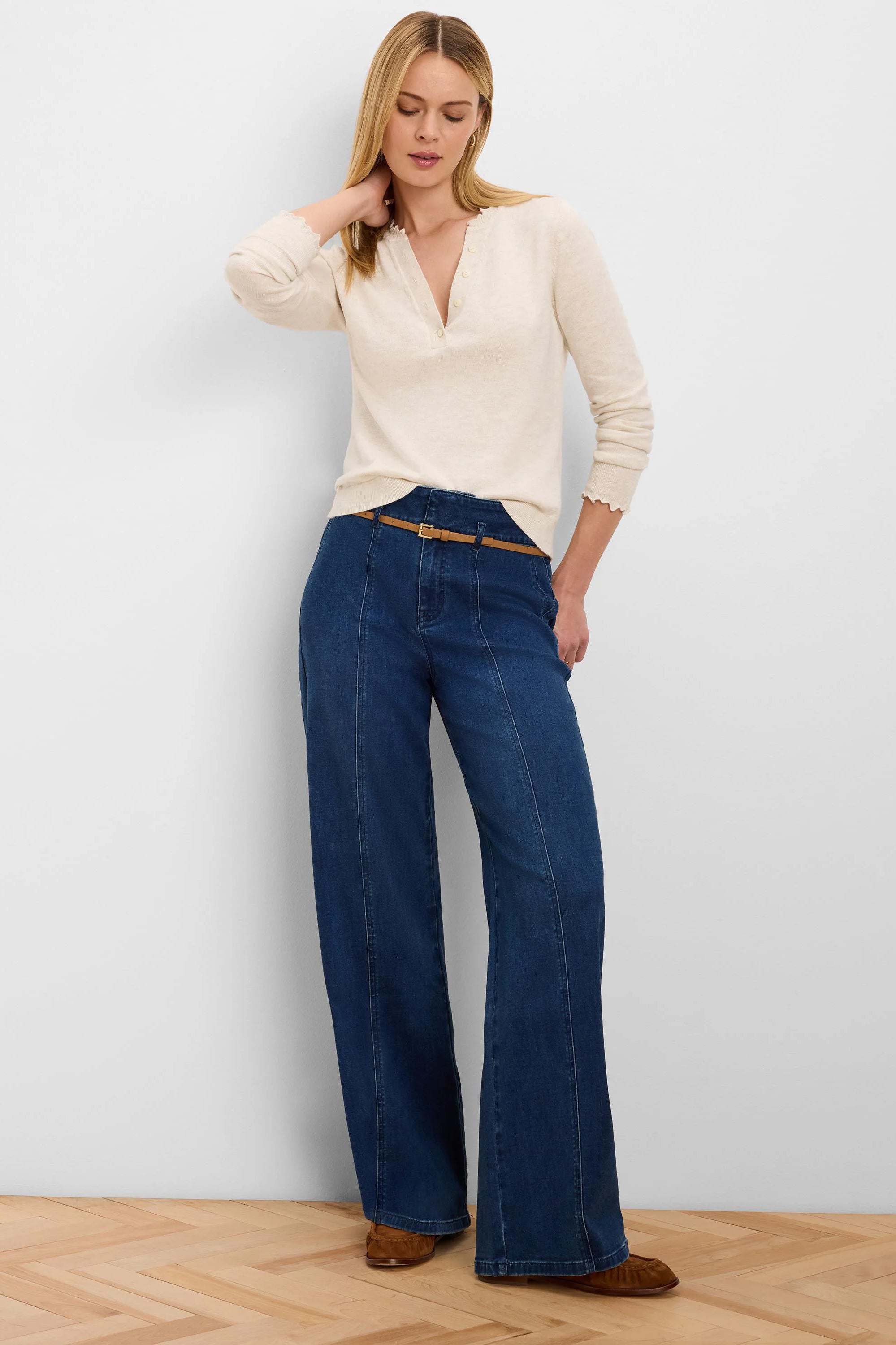 Dark blue wide-leg belted jeans with vertical front seams and a thin tan belt.