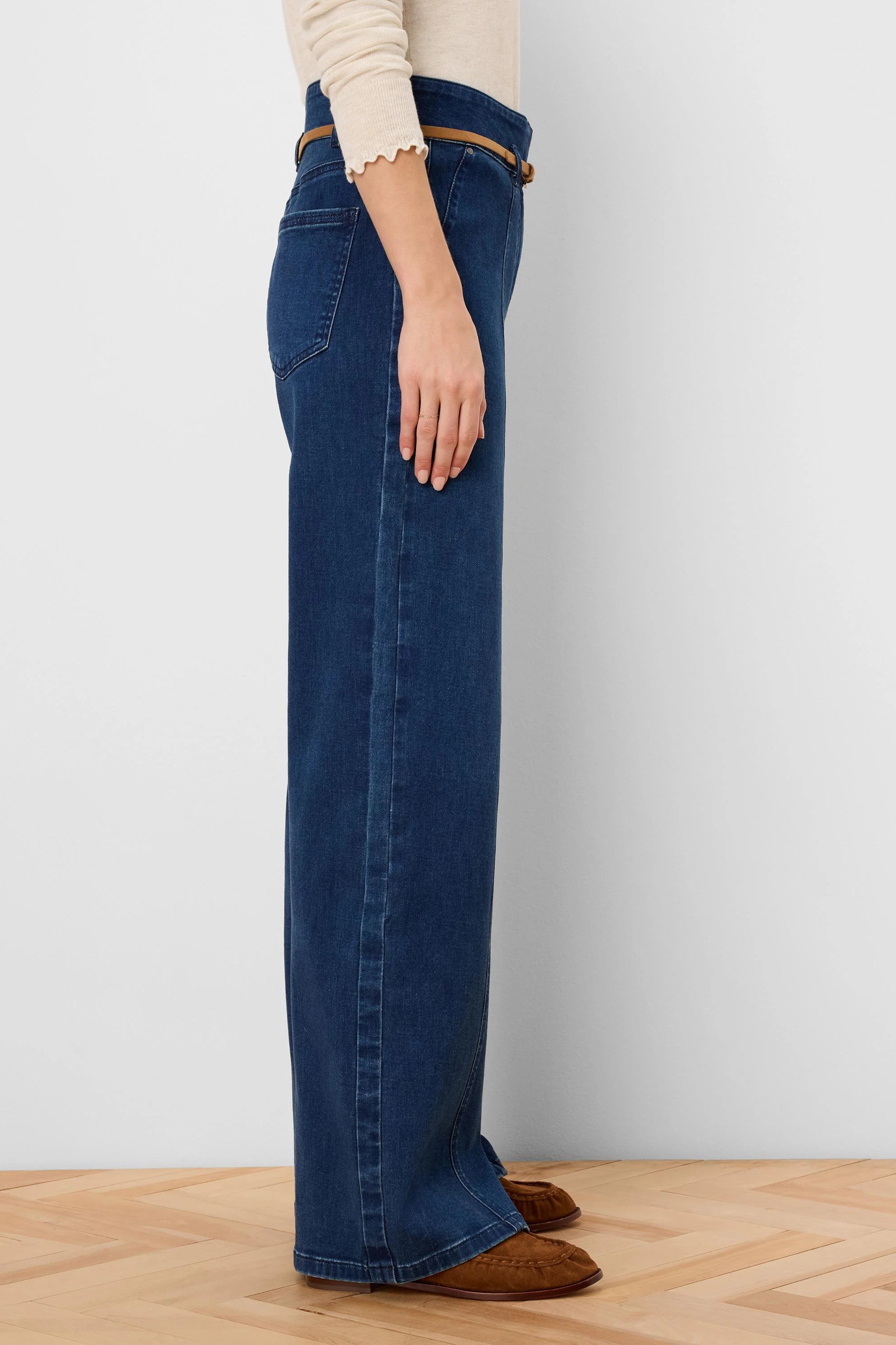 Dark blue wide leg jeans, side view. Features a thin tan belt at the high waist.