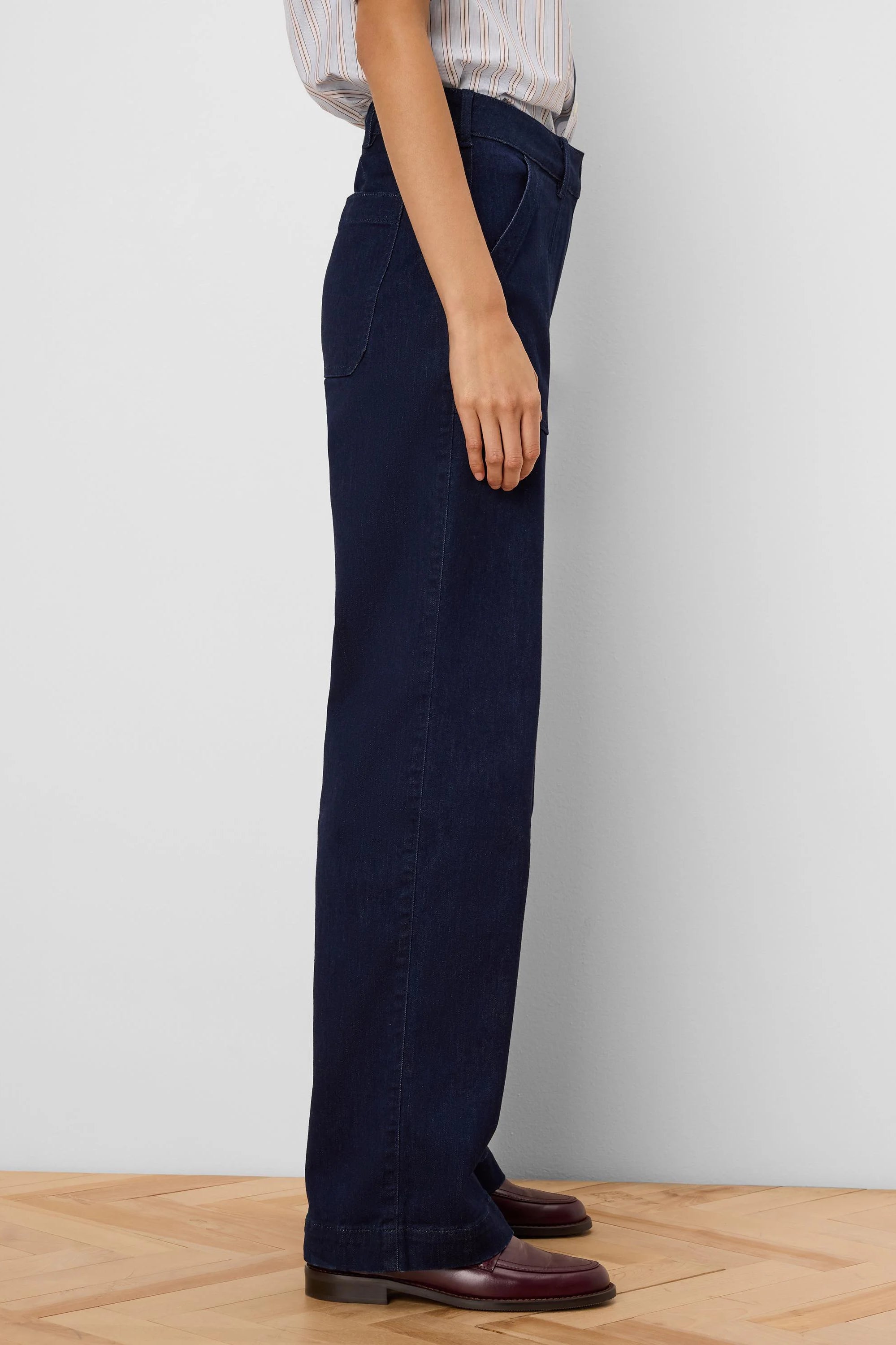 Dark indigo wide-leg jeans with a visible folded cuff, viewed from the side on a model.