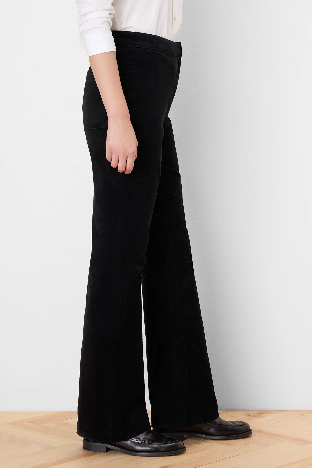 Black velvet high-rise boot-cut pants, side view. Legs flare widely from the knee, covering the feet.