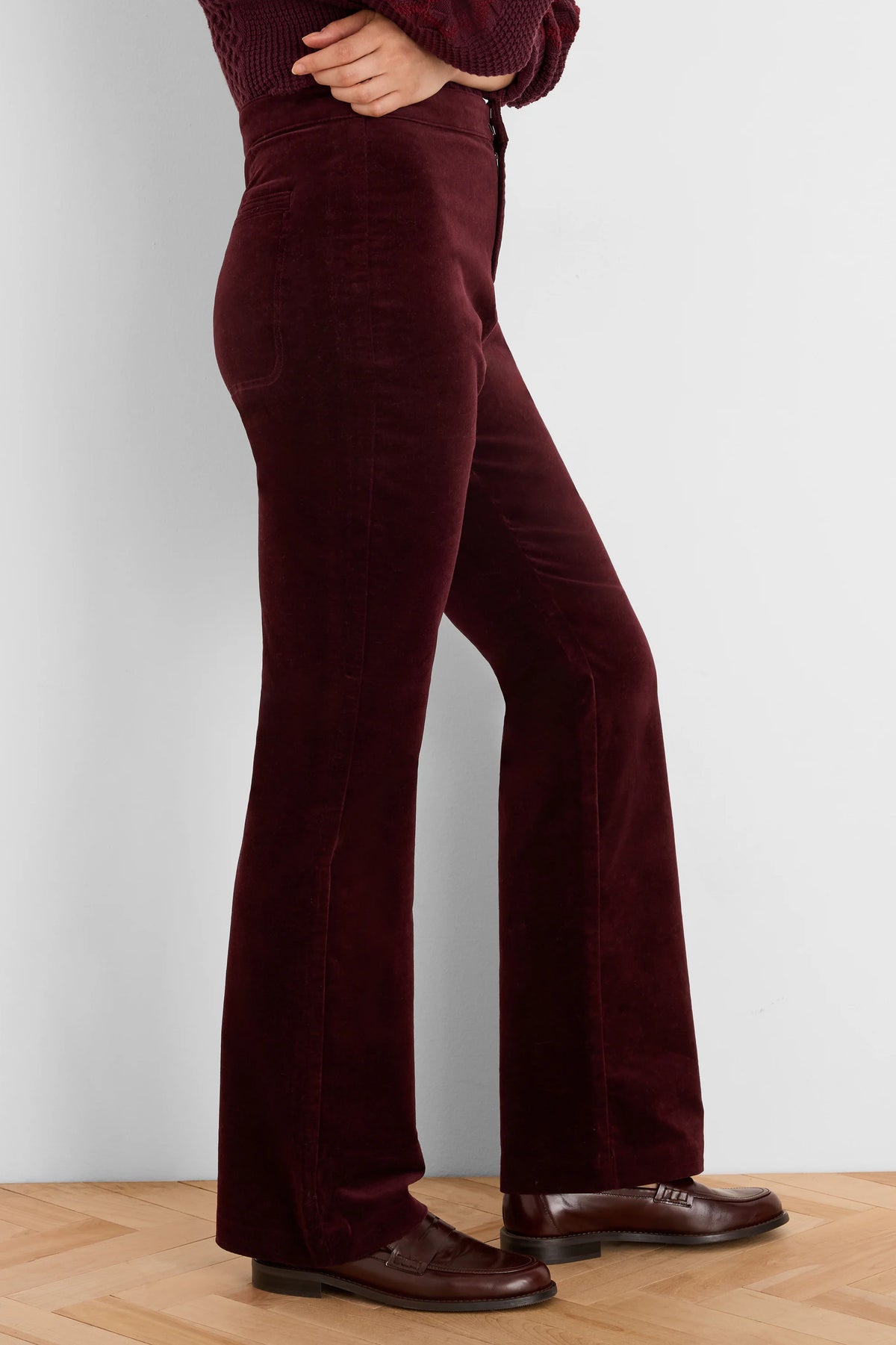 Dark red velvet high-waisted boot-cut pants with a flared leg, showcasing the fabric's soft sheen.