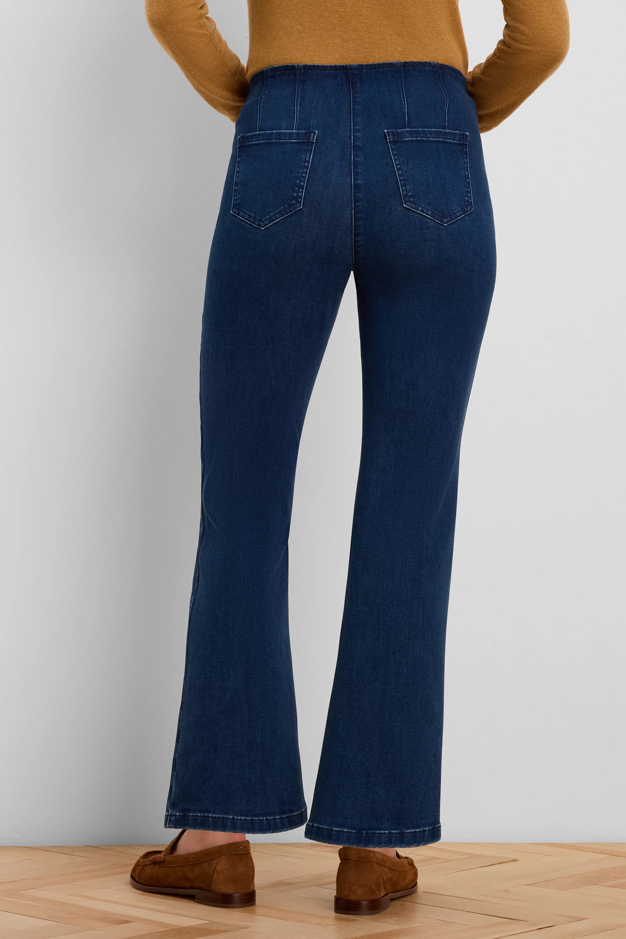 Dark blue boot-cut jeans, rear view. High waist with gathered back, two back pockets, and flared hems.