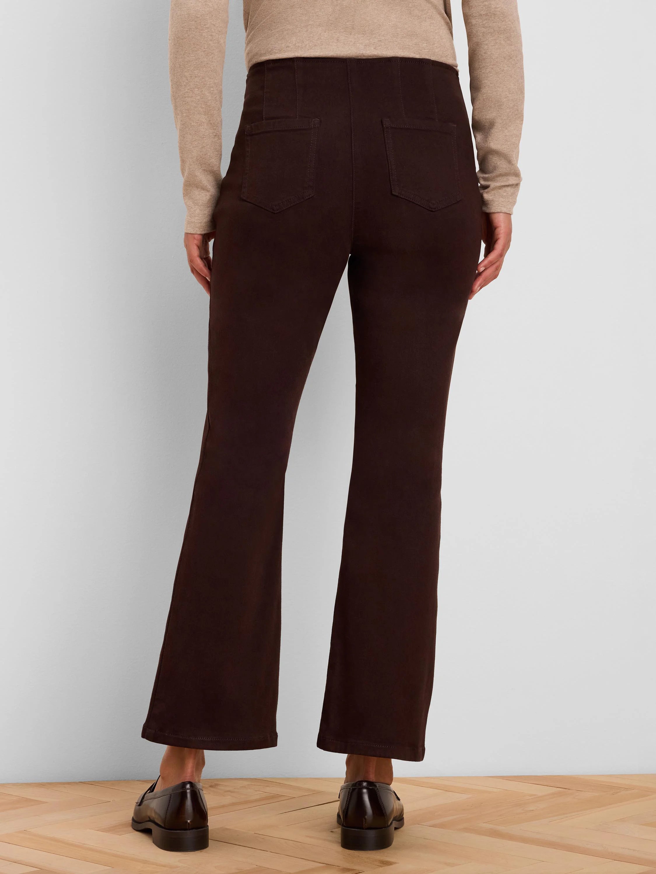 Dark brown bootcut jeans, high-waisted, with two visible back patch pockets and a subtle leg flare.