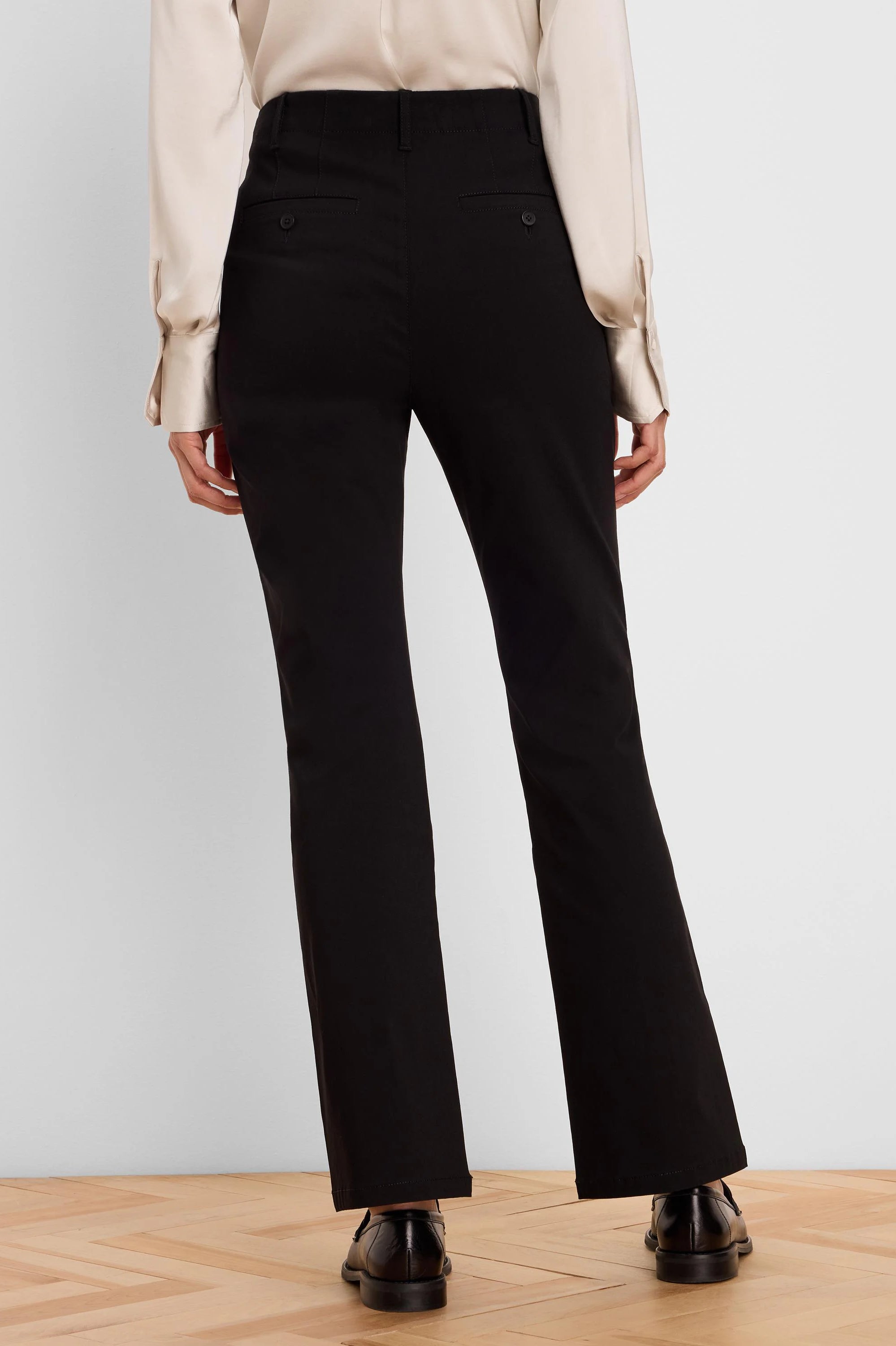 Black high-rise bootcut pants shown from the back, with small buttoned back pockets.