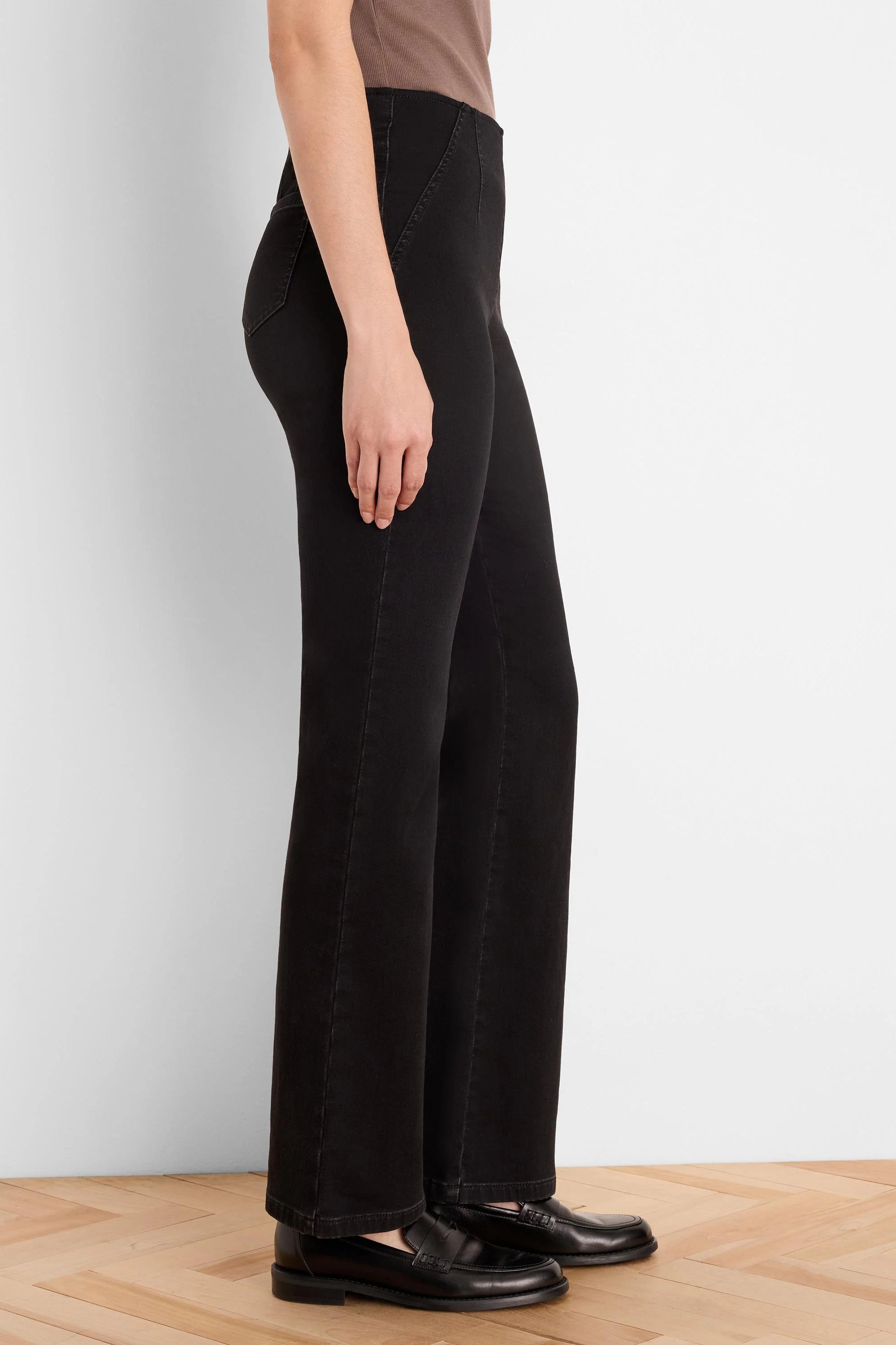 Black bootcut jeans, modeled from the side. They have a slight flare below the knee and subtle vertical seams.
