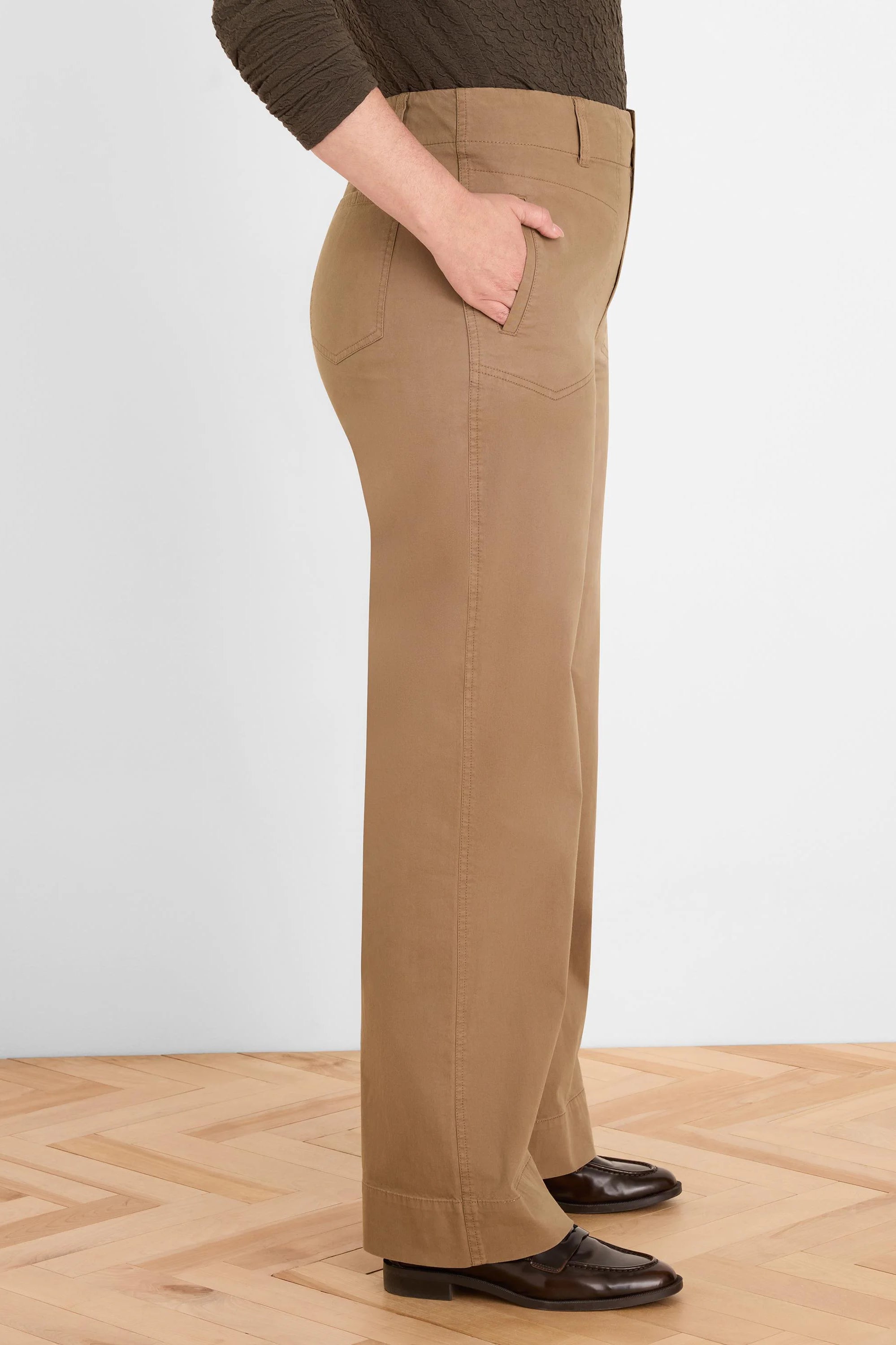 Tan wide-leg pants with angled front pockets, belt loops, and visible stitching, shown on a model from the side.