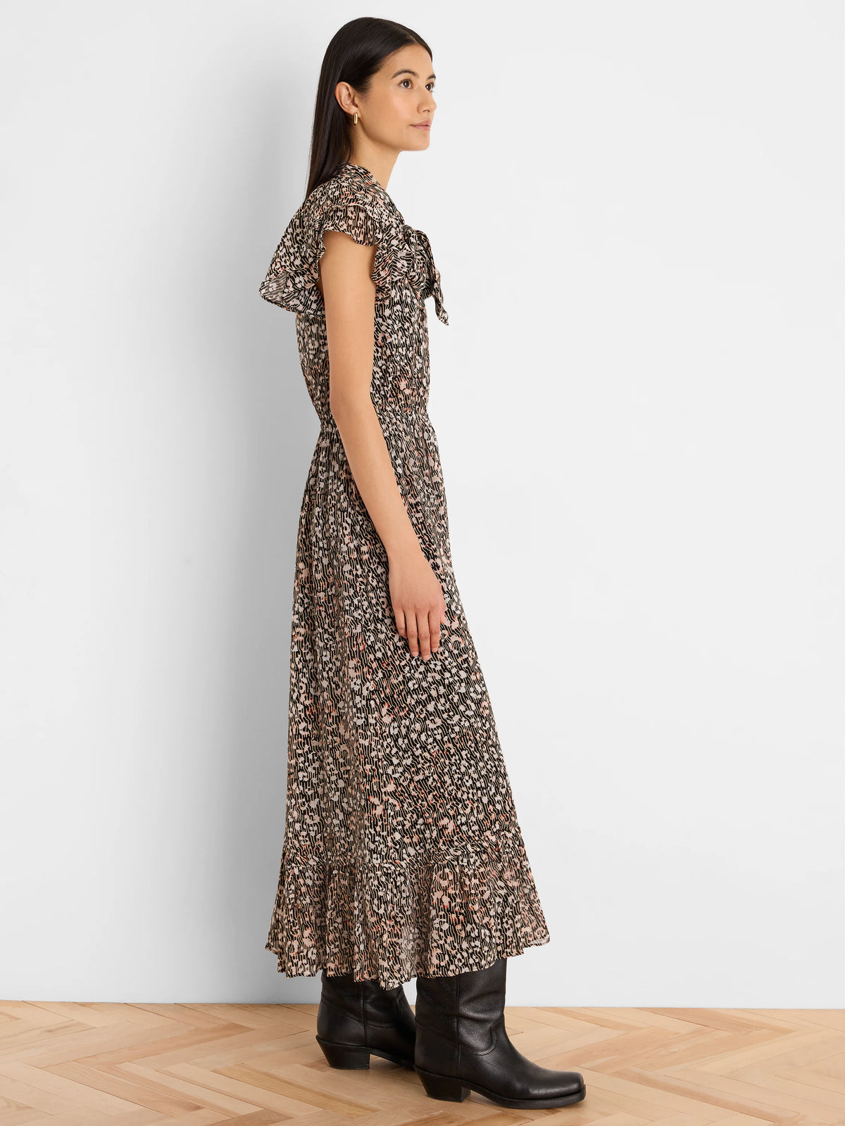 Maxi dress with dark brown, tan & peach abstract print. Features ruffled short sleeves, tie neck, & cinched waist.