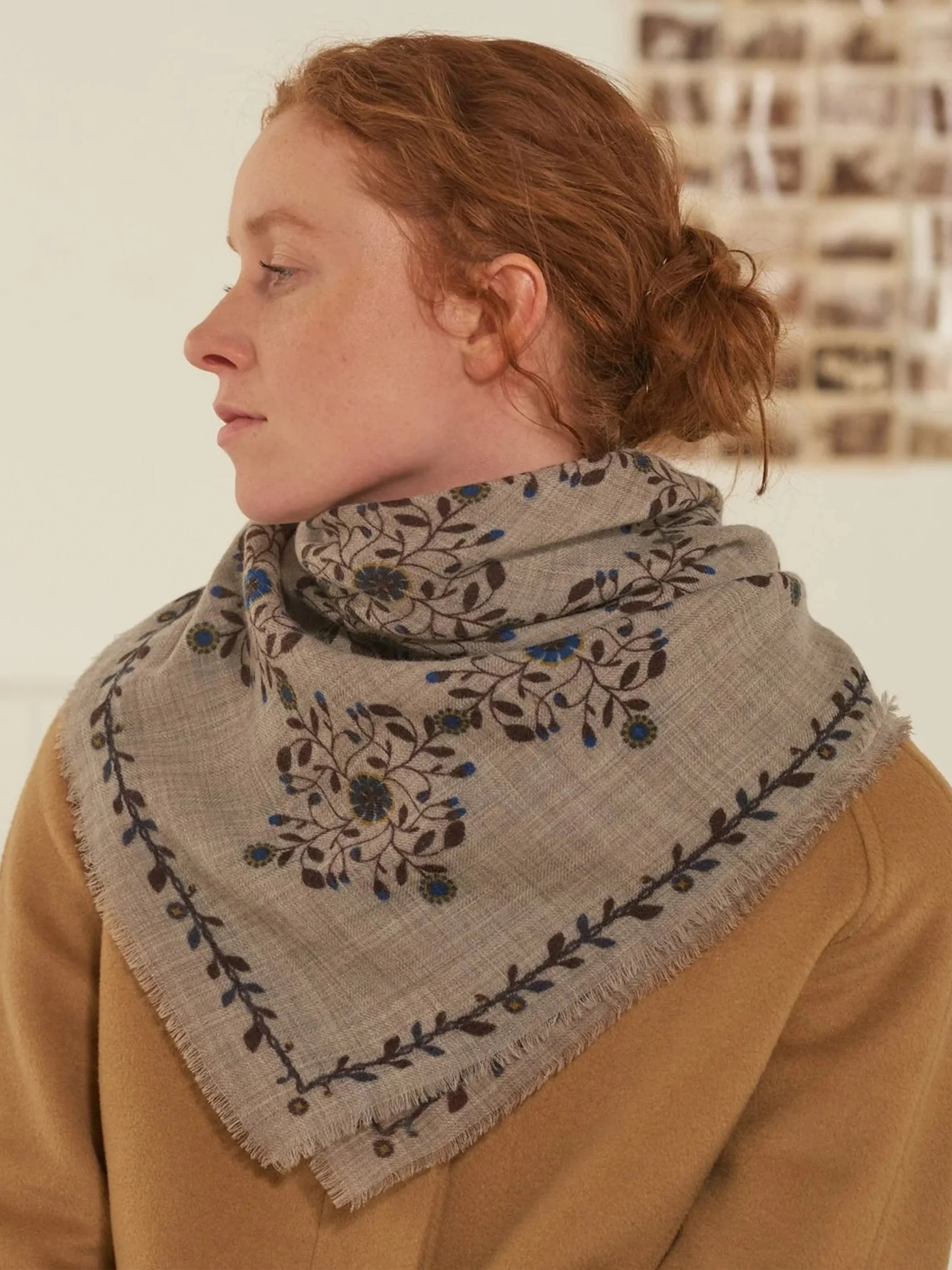 Beige square scarf with dark brown and blue floral pattern and frayed edges.