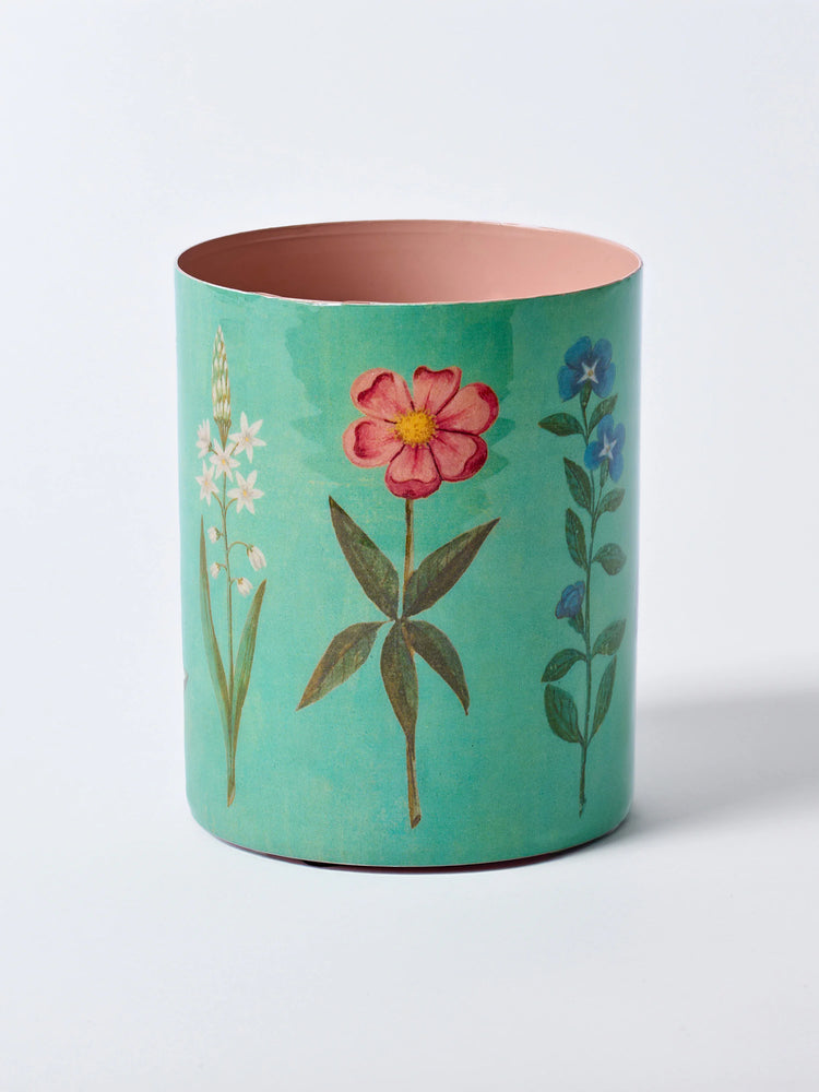 Teal enamel pot with pink interior. Exterior features botanical illustrations of white, pink, and blue flowers.