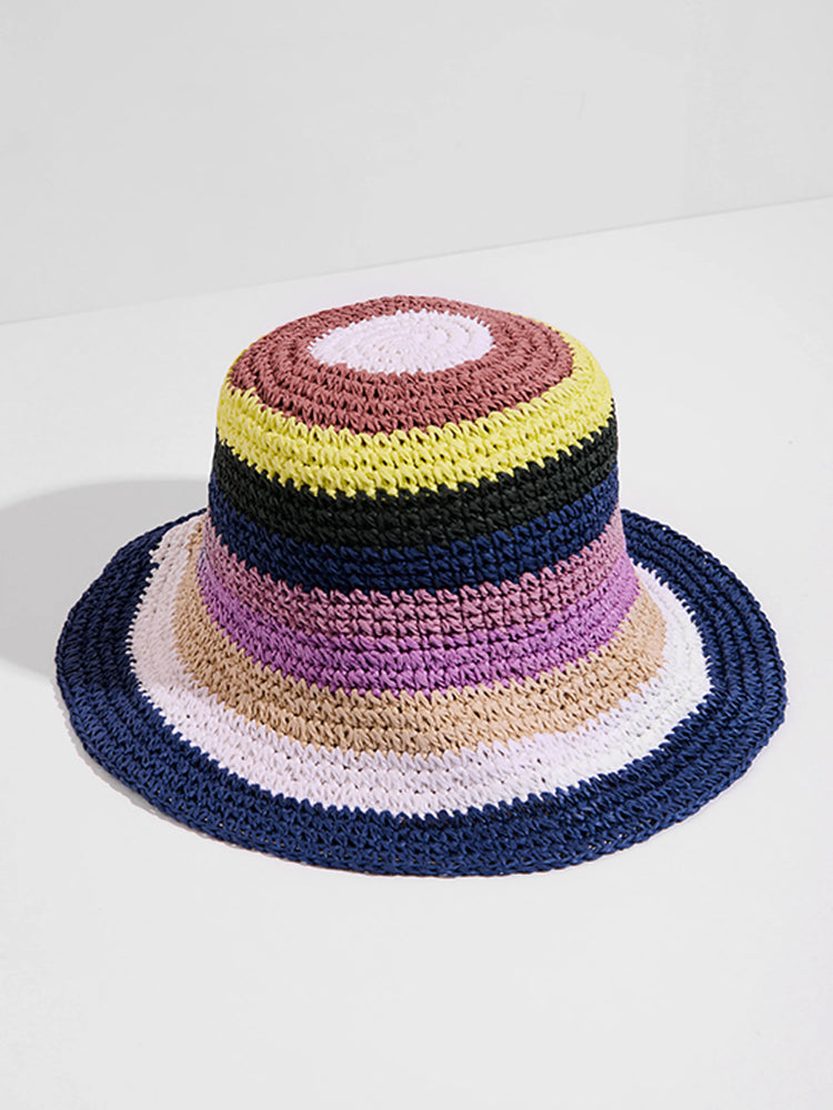 Multicolored crocheted bucket hat. Features horizontal stripes of mauve, white, beige, purple, dark blue, black, and...